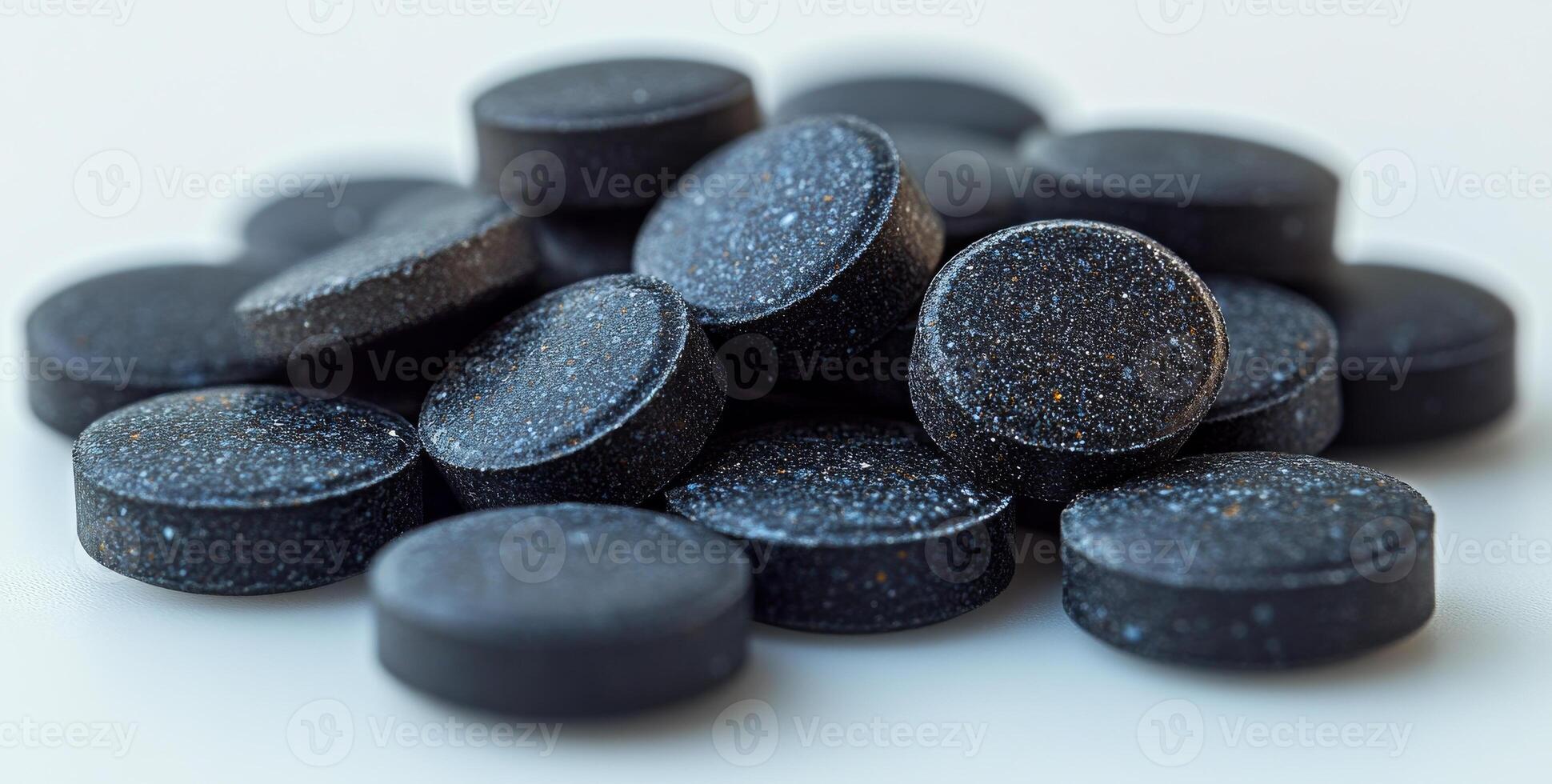 A pile of black pills on a white surface. The pills are small and round, and they are all the same color. Concept of uniformity and order, as the pills are neatly stacked on top of each other photo