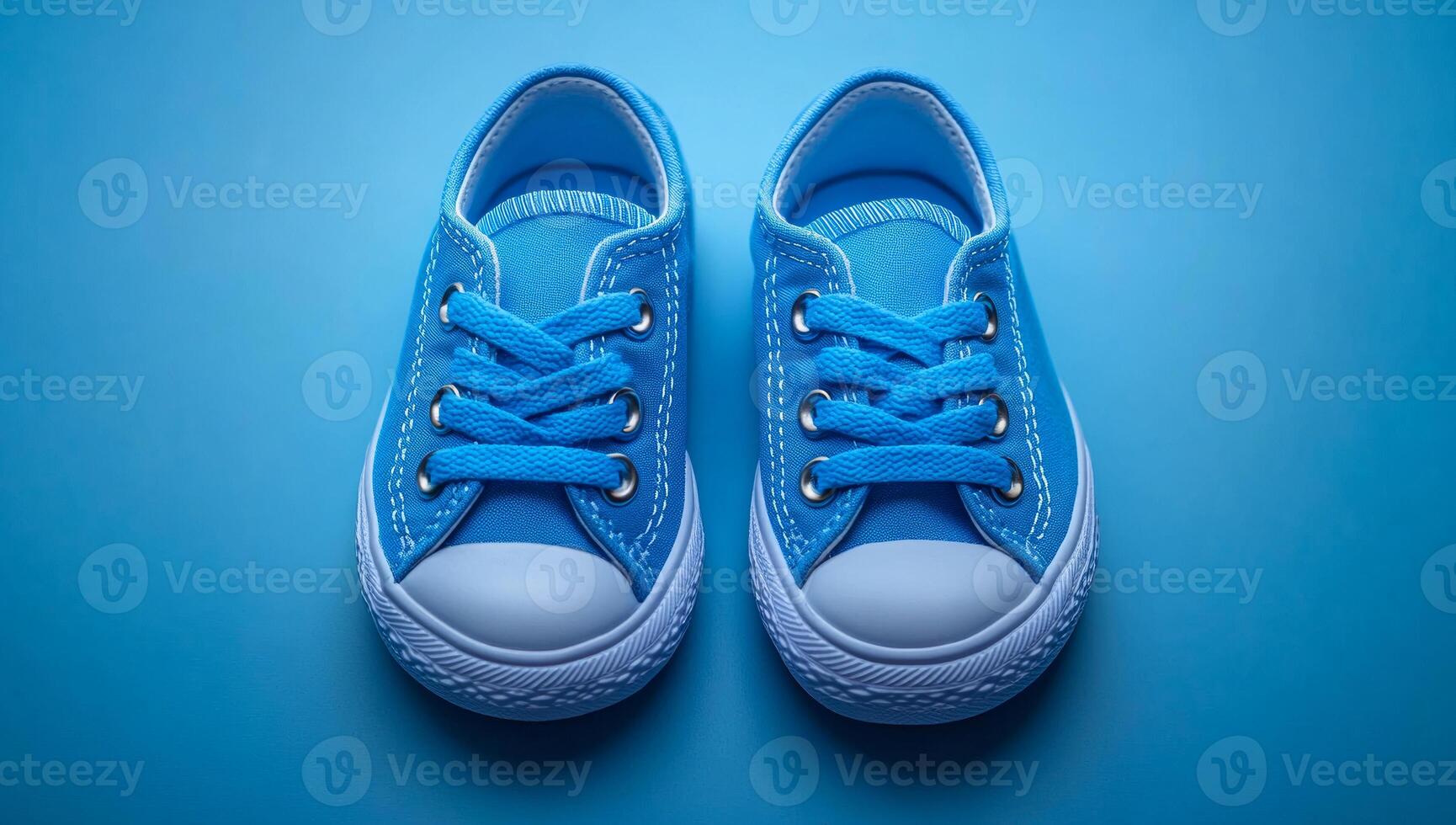Two blue Converse sneakers are on a blue background. The sneakers are the same color and are positioned next to each other photo