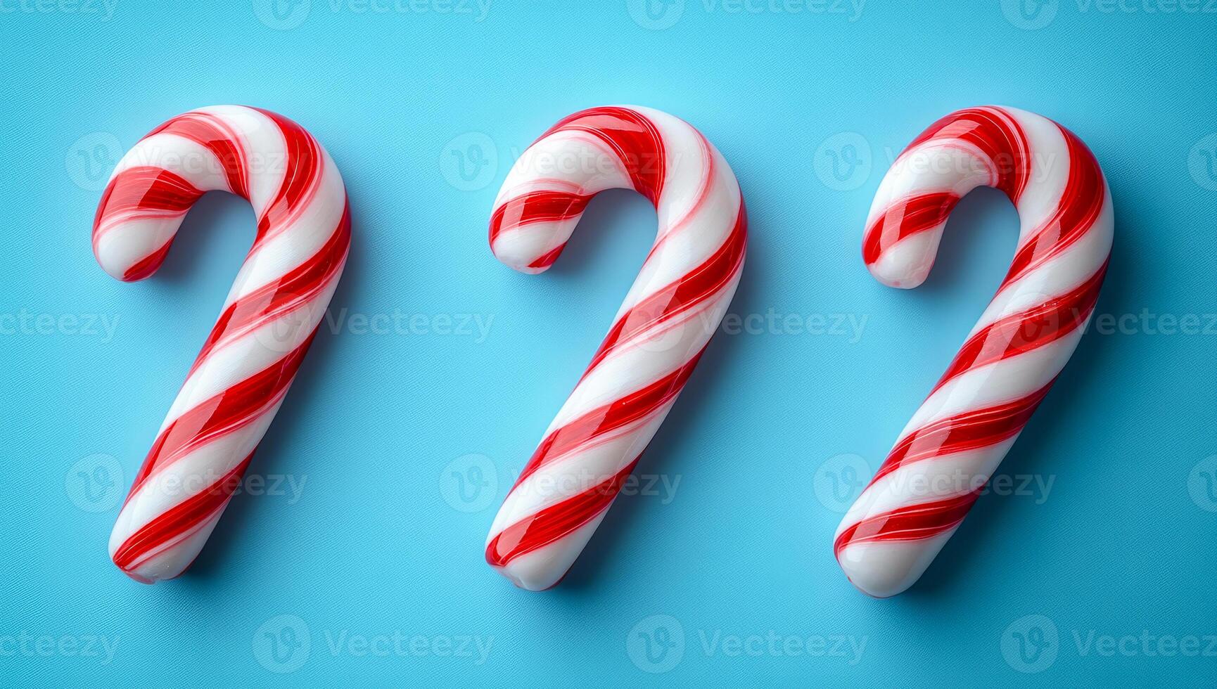 Three red and white candy canes are arranged on a blue background. The candy canes are placed in a row, with the middle one slightly overlapping the other two. The arrangement creates a festive photo