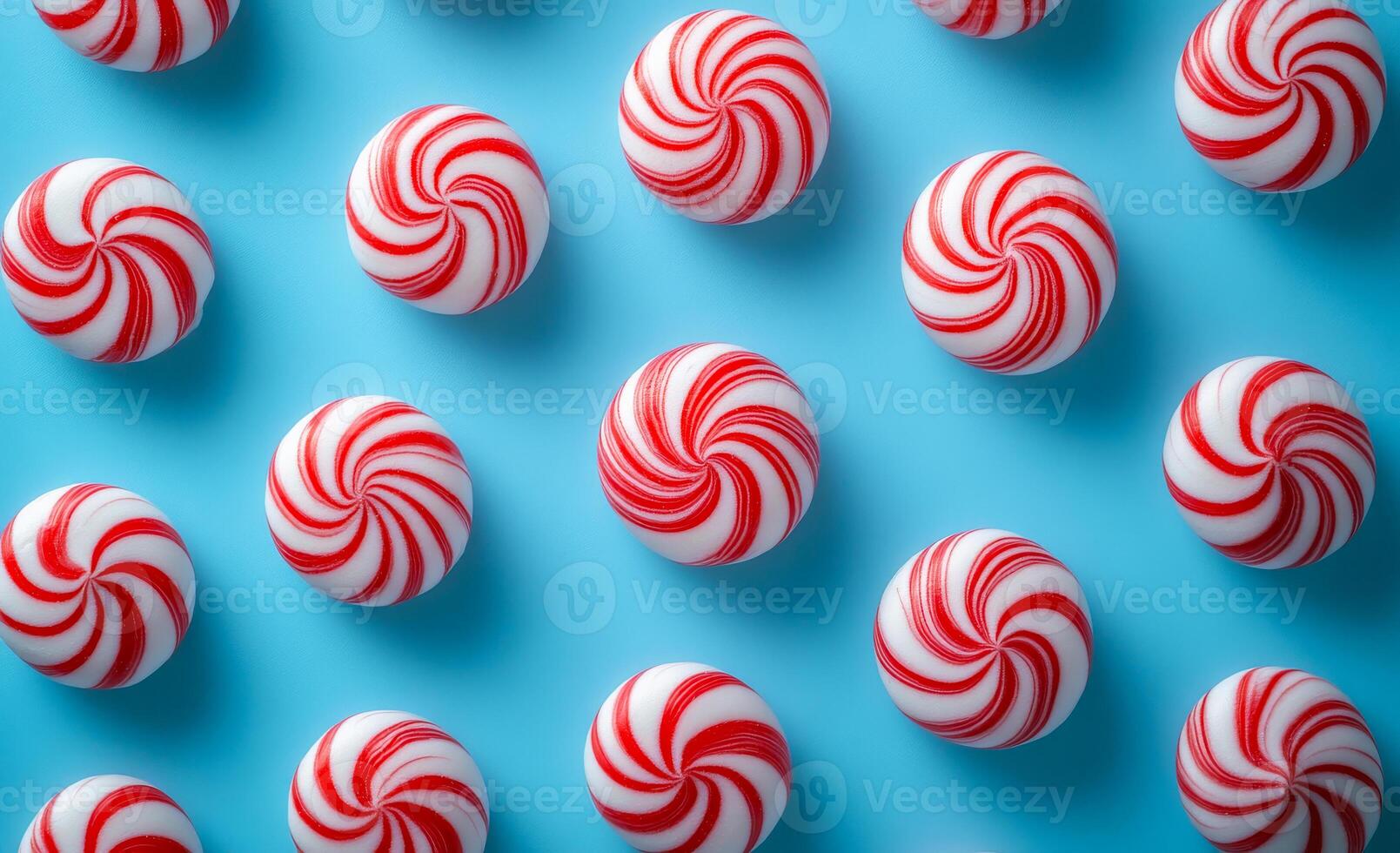 A row of red and white candy canes are arranged in a spiral pattern. The candy canes are placed in a blue background, creating a festive and cheerful atmosphere photo