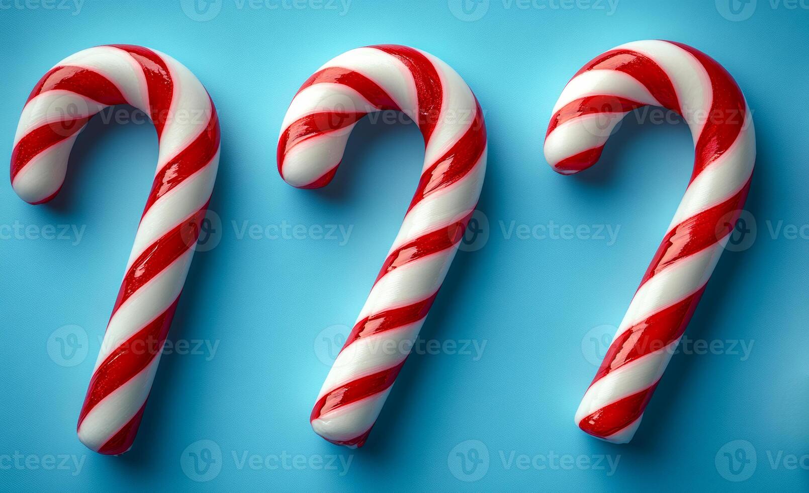 Three red and white candy canes are arranged on a blue background. The candy canes are placed in a row, with one slightly overlapping the other two. The arrangement creates a festive and cheerful mood photo