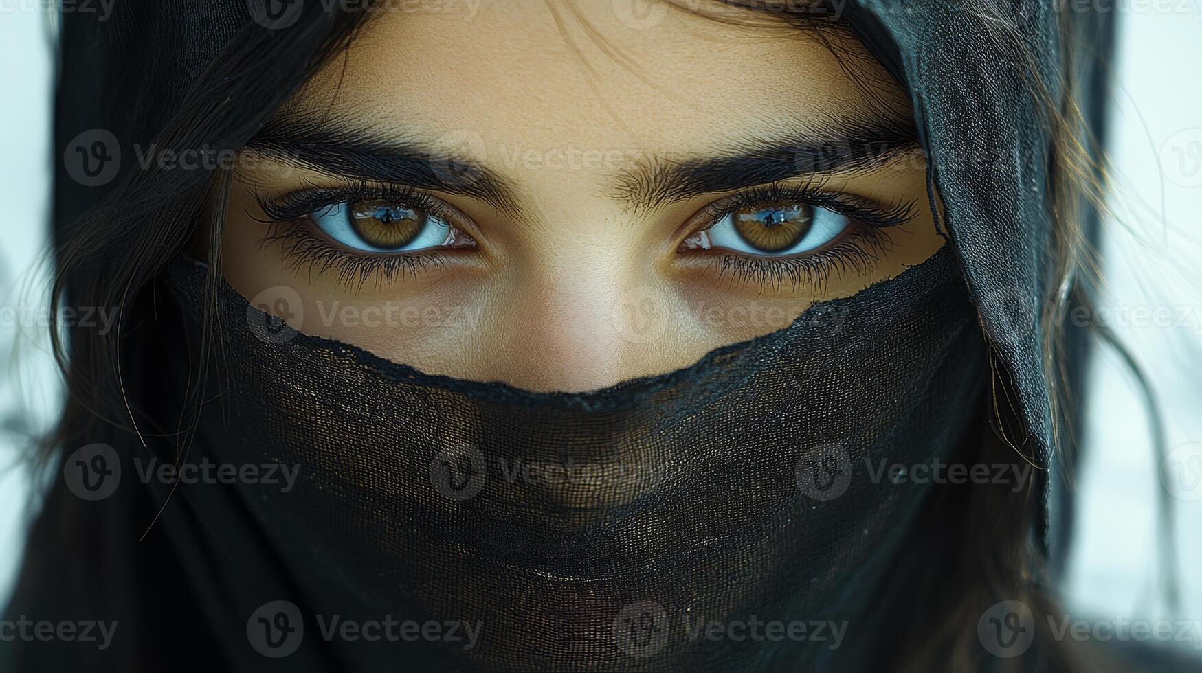 A woman with brown eyes and a black scarf covering her face. photo