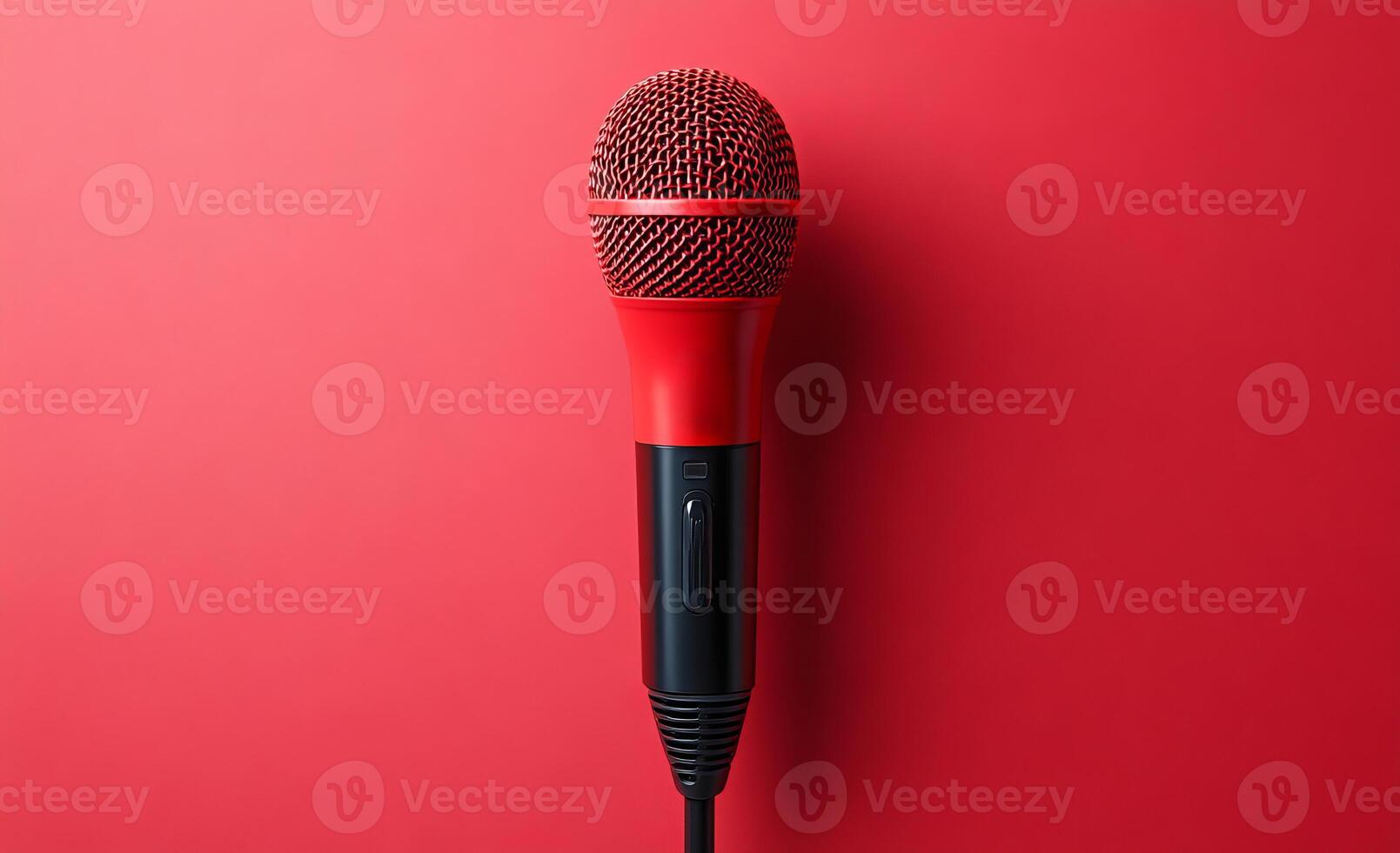 Red mic on vibrant studio backdrop. A bright red microphone stands upright against a bold red background, ready for a performance or recording session in a studio setting. photo