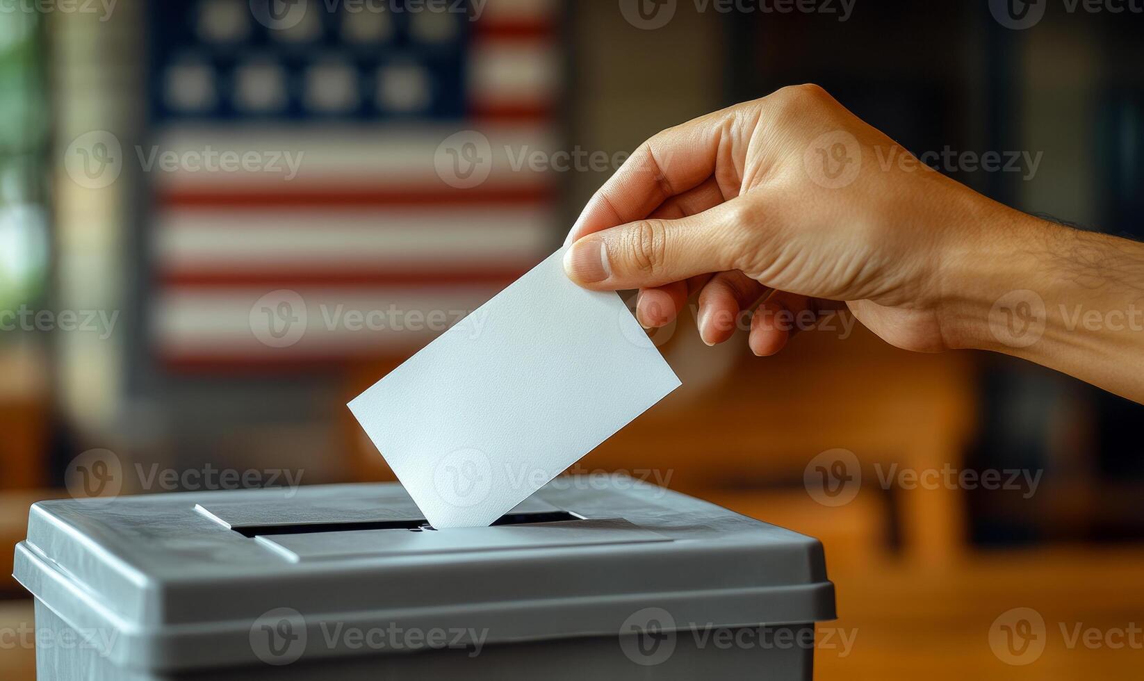 Casting a ballot in a local voting booth. A hand places a ballot into a gray voting box in a polling station with an American flag in the background. photo