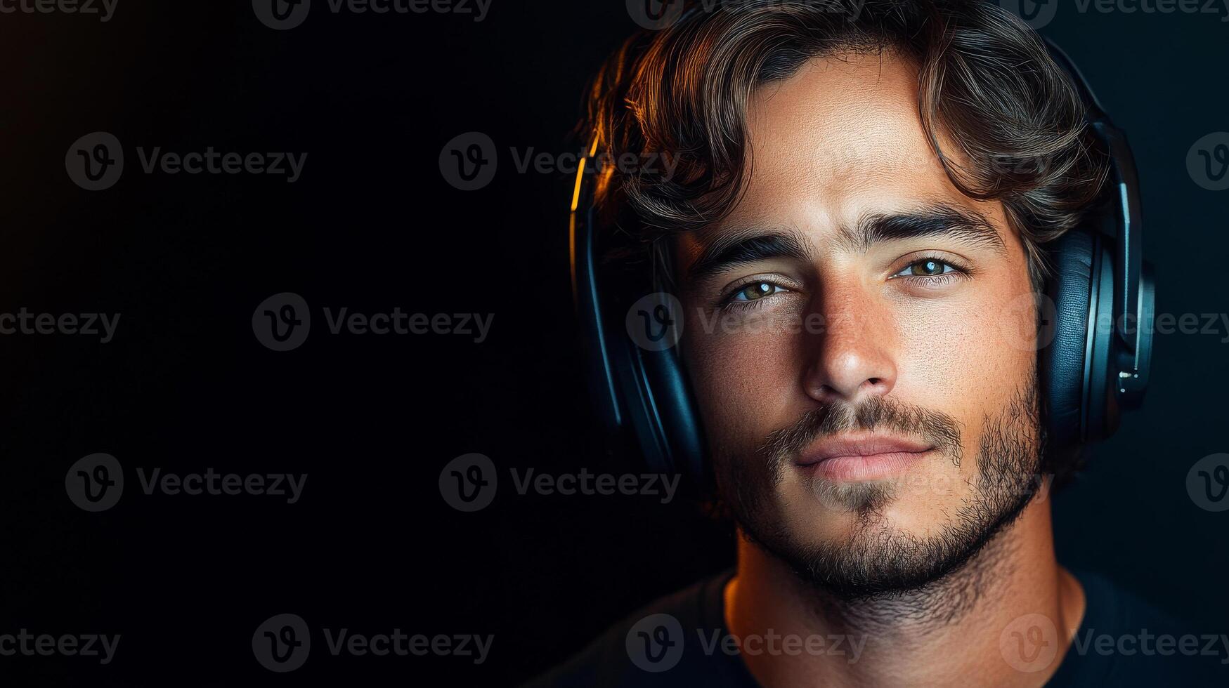 A man with a beard and glasses is wearing headphones. He is smiling and looking at the camera photo