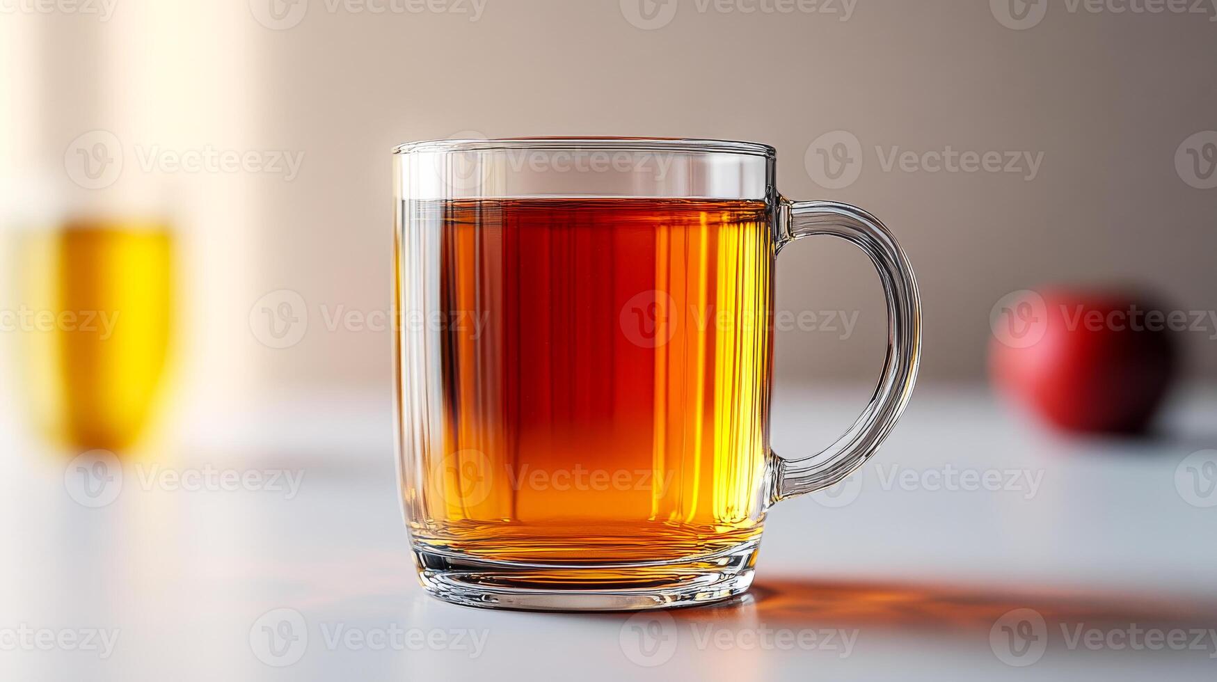 A glass of tea sits on a table with a red apple in the background. Concept of relaxation and comfort, as the warm beverage is often associated with calming moments. The apple adds a touch of freshness photo