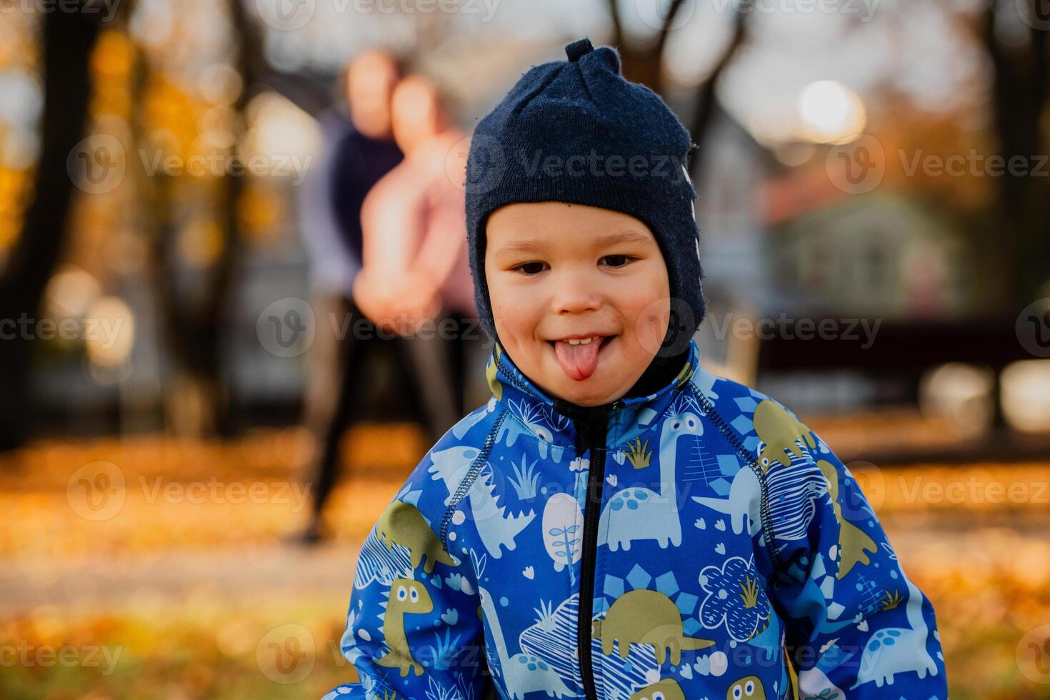 A joyful little boy in his winter coat and hat plays happily in the park, surrounded by the love and warmth of his smiling parents photo