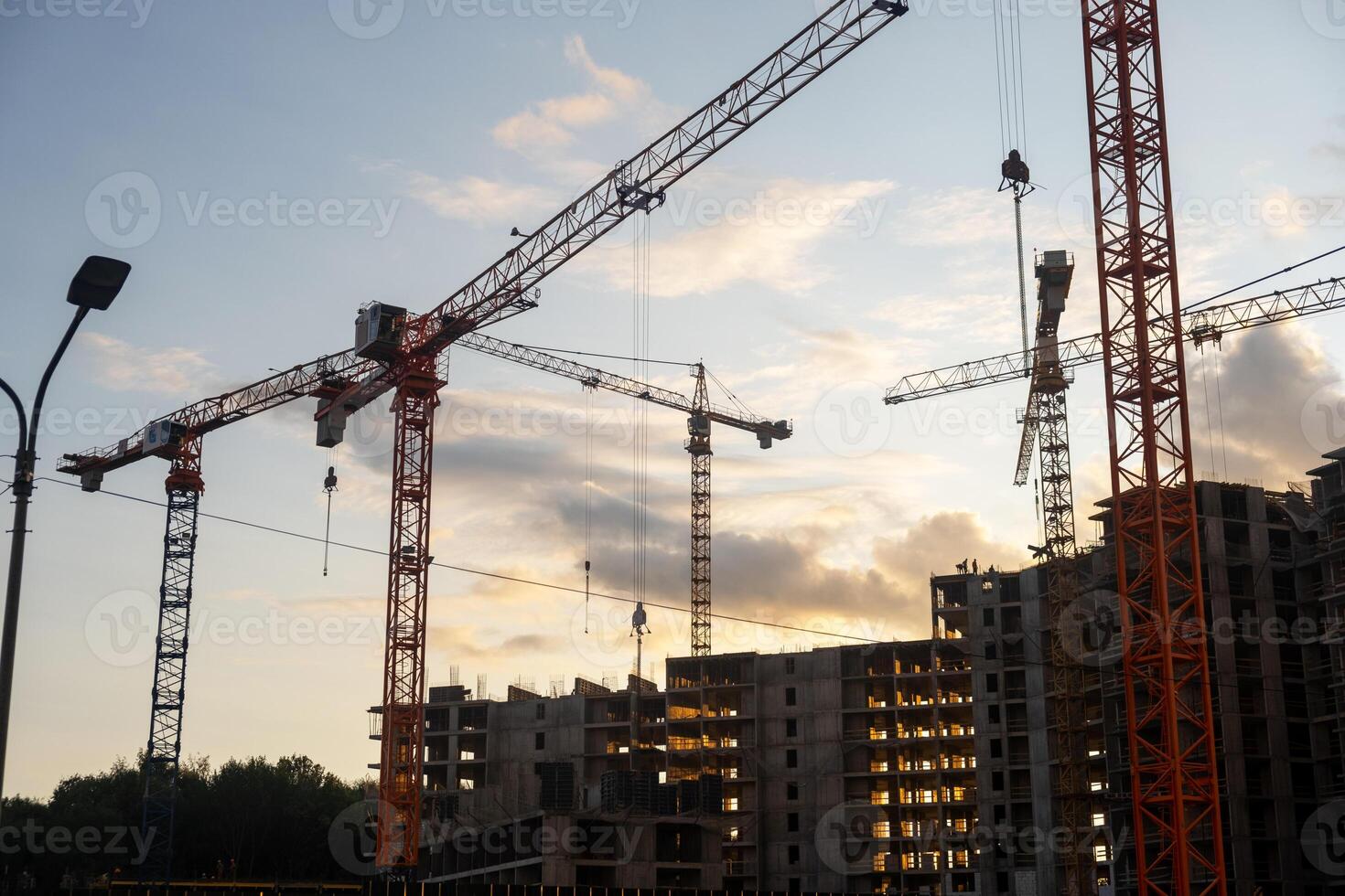 Multiple cranes operate efficiently at a bustling construction site, showcasing the progress of urban development during sunset hours photo