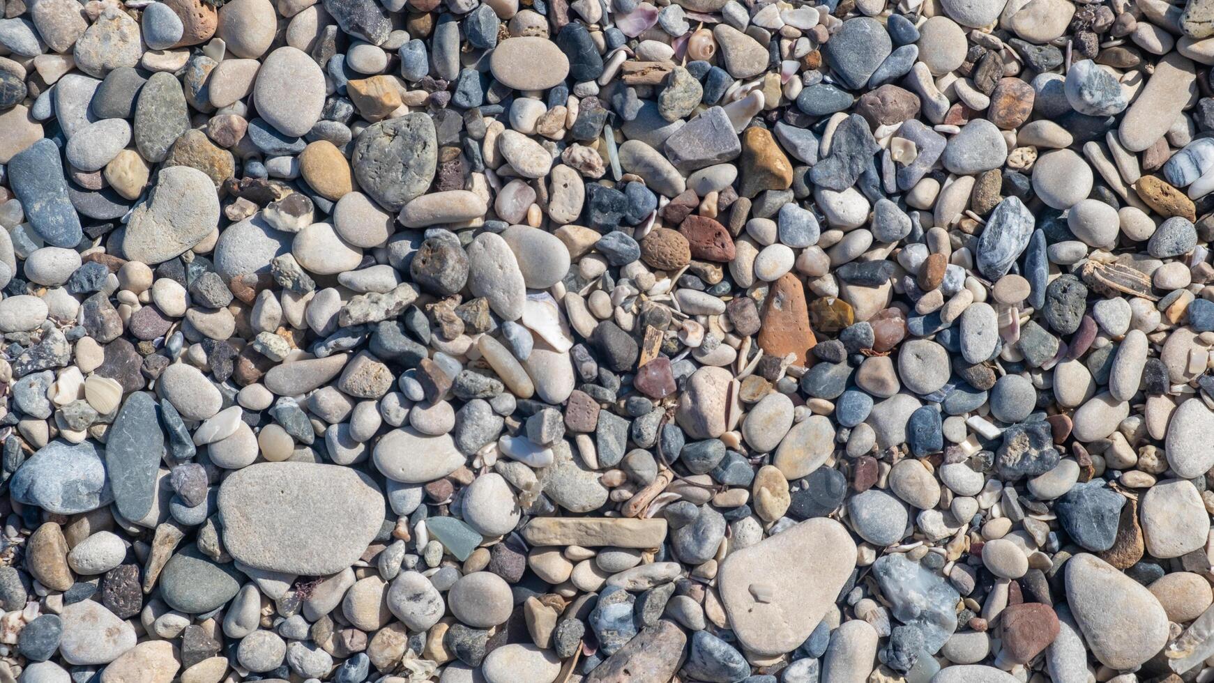 The beach showcases a diverse collection of smooth and colorful pebbles scattered along the shore, reflecting the tranquility of the day photo