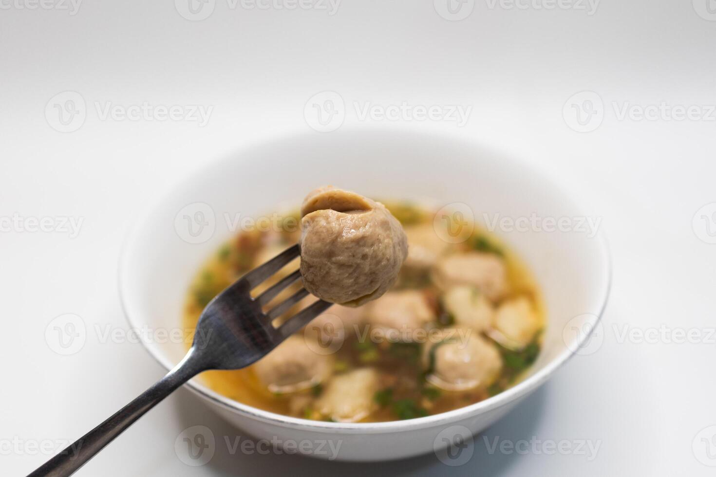 Meatball on Fork in Soup Bowl. photo