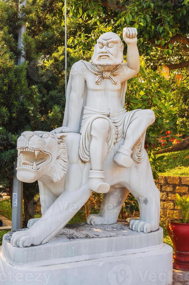 white Buddhist statue of Buddha sitting on a lion in park at the Linh Ung Pagoda in Da Nang in Vietnam in summer in Asia photo