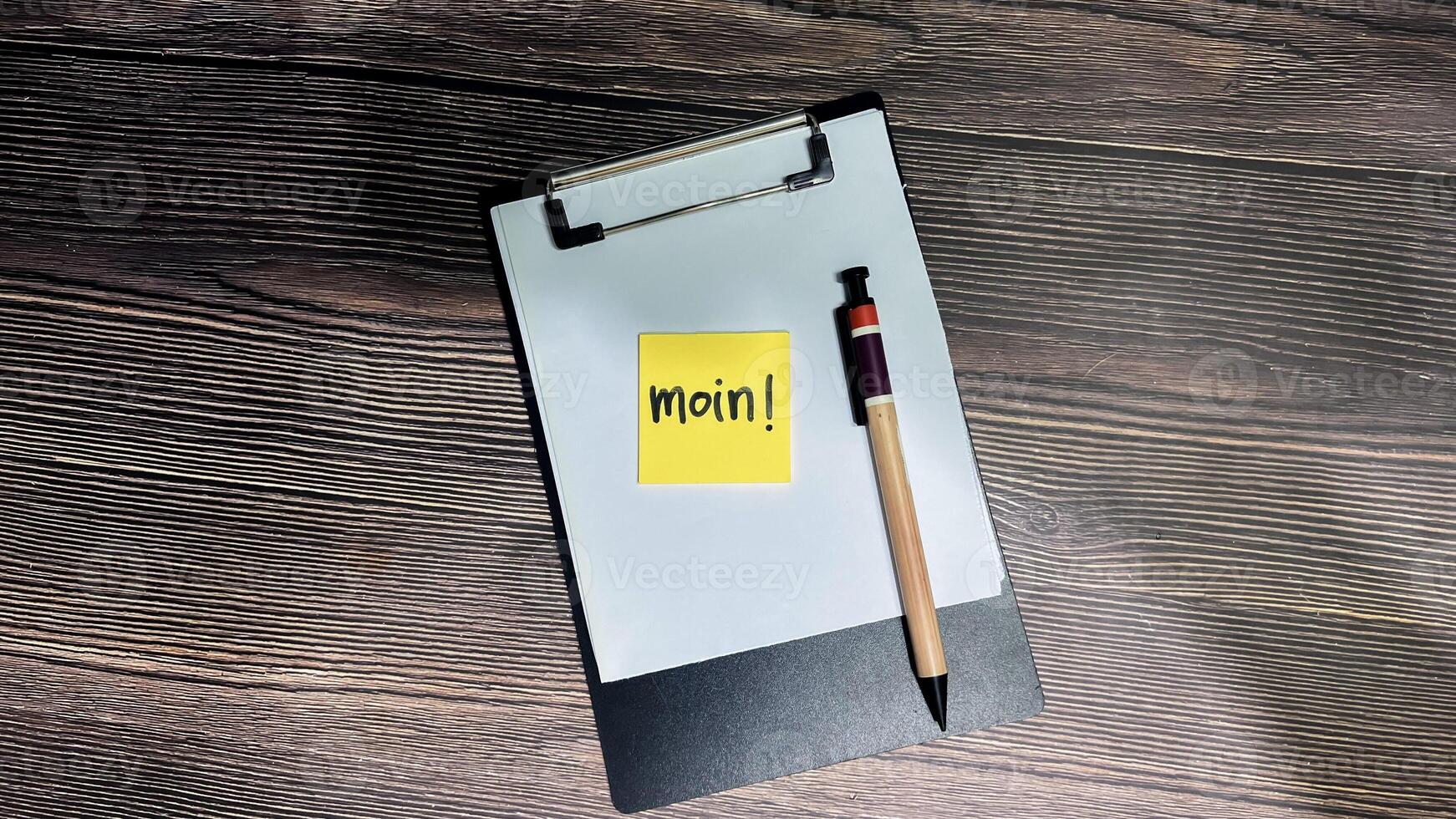 Concept of Moin on German Language write on sticky notes isolated on Wooden Table. German Language it means Good morning photo