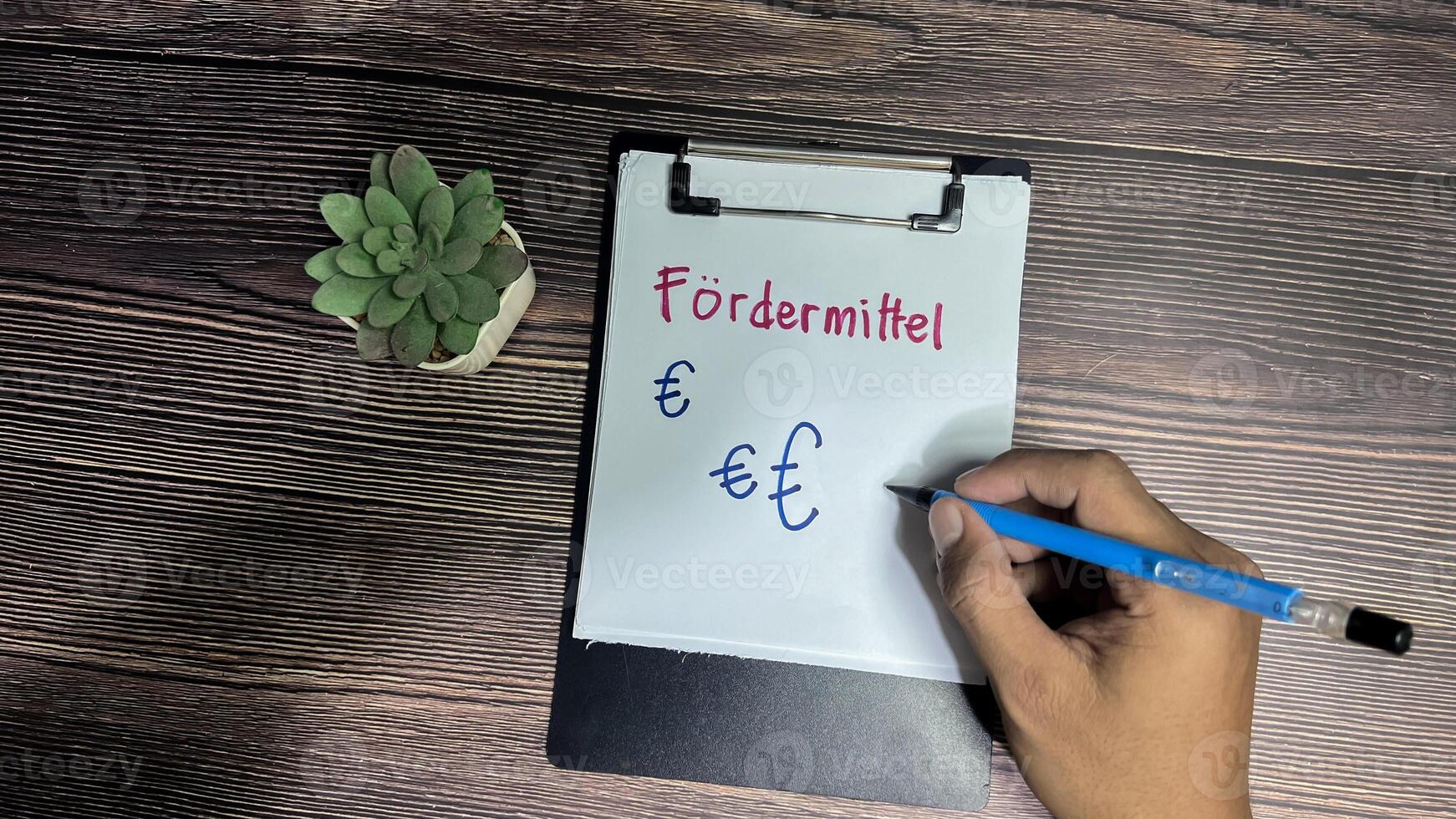 Concept of Fordermittel on German Language write on paperwork isolated on Wooden Table. German Language it means funding photo