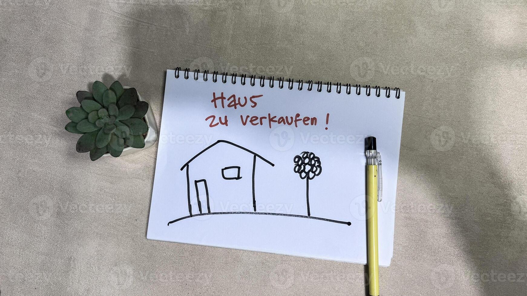 Concept of Haus Zu verkaufen on German Language write on book isolated on Wooden Table. German Language it means House For sale photo