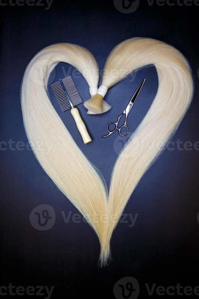 hair extension equipment of natural blonde hair. heart shape on a dark background. photo