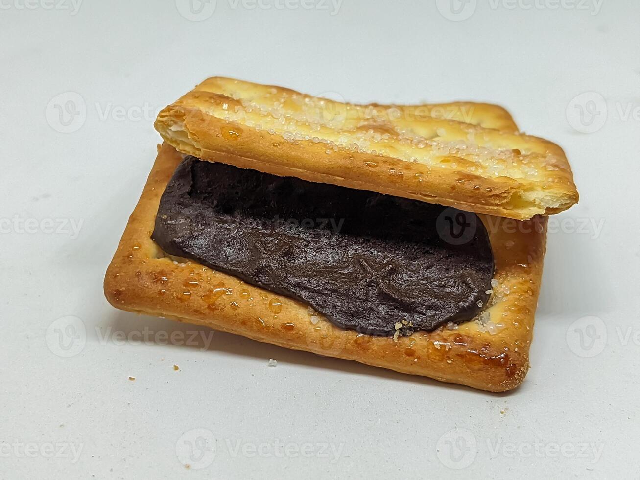 A tempting open view of a chocolate-filled biscuit, emphasizing the glossy chocolate against the crisp biscuit. The presentation invites dessert lovers to enjoy this delectable treat. photo