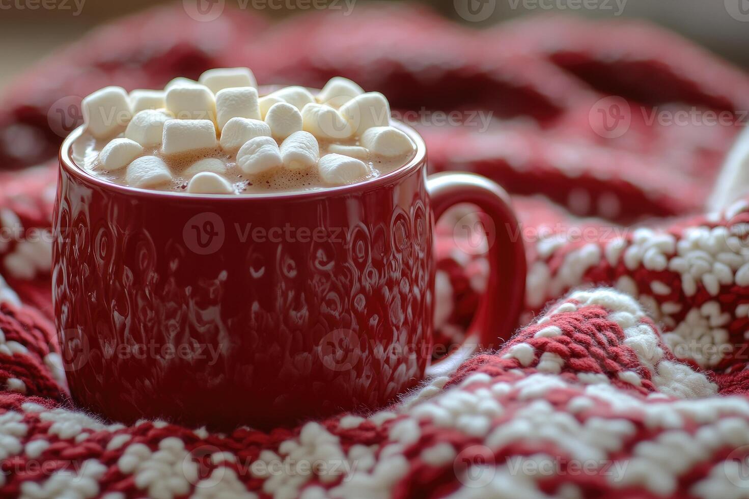 Red mug containing hot chocolate with marshmallows warming on a cozy christmas blanket photo