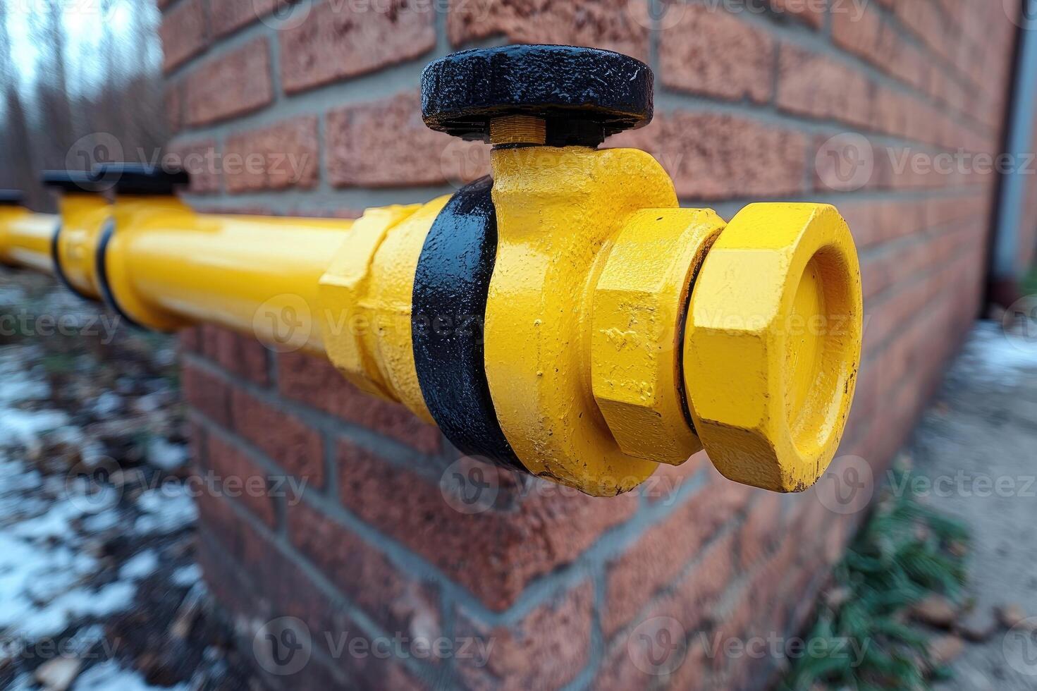 Yellow gas pipe emerging from brick wall with flange and bolts photo
