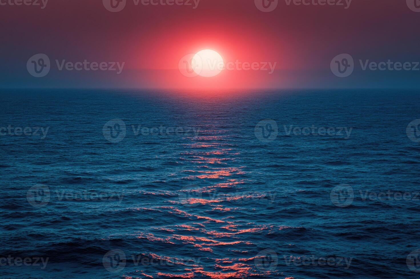 Big red sun setting on calm ocean creating pink reflections photo
