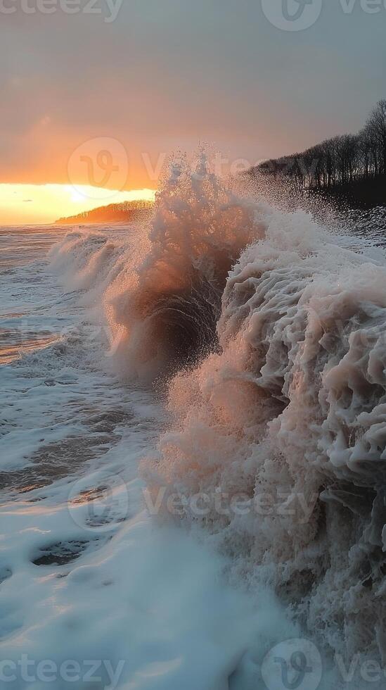 Big waves crashing on shore at sunset with cloudy sky and coastline photo