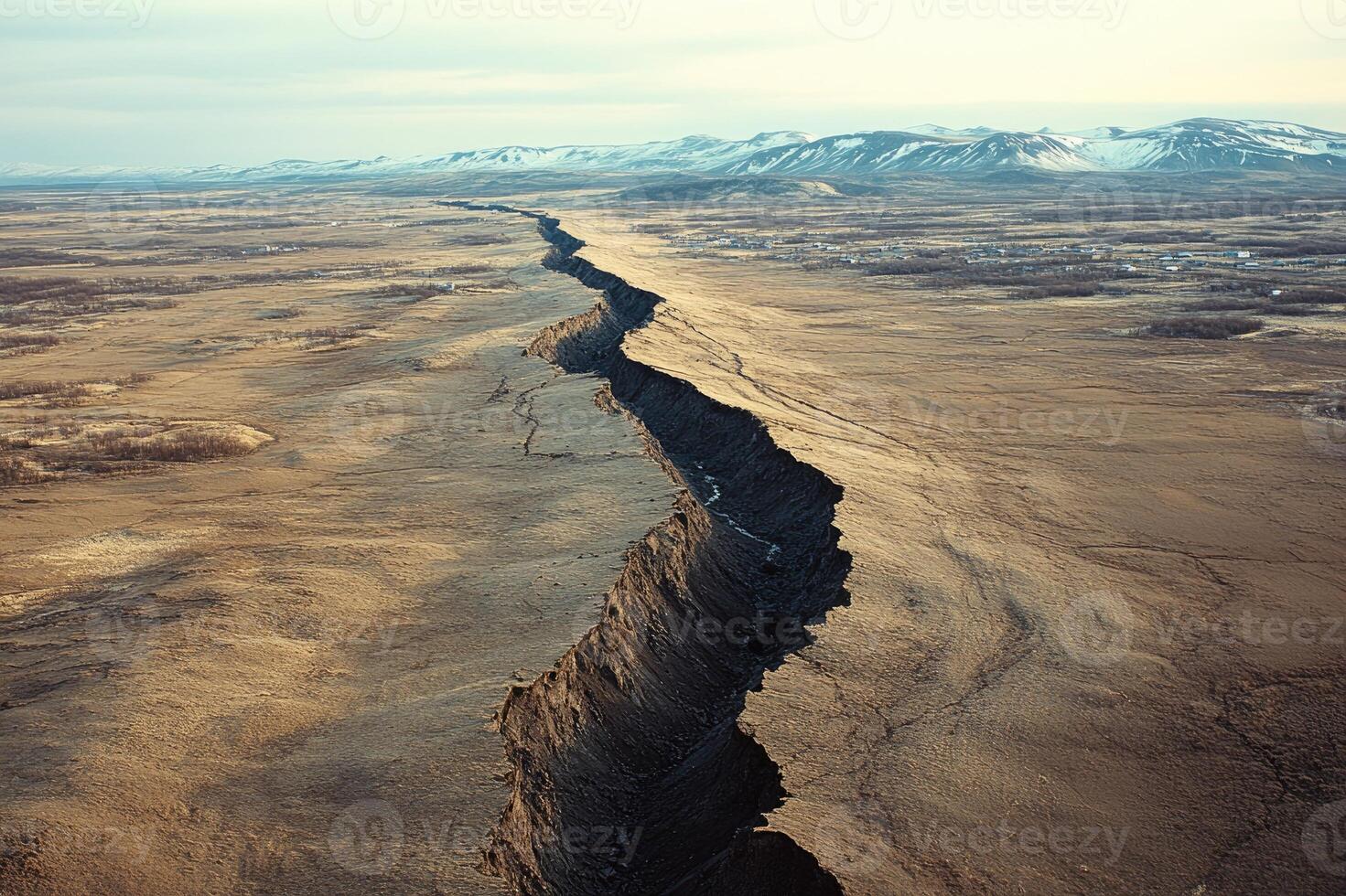 Deep canyon dividing the vast icelandic plains near a distant town photo