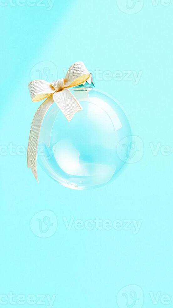 Transparent Christmas Ornament with White Bow on Blue Background photo