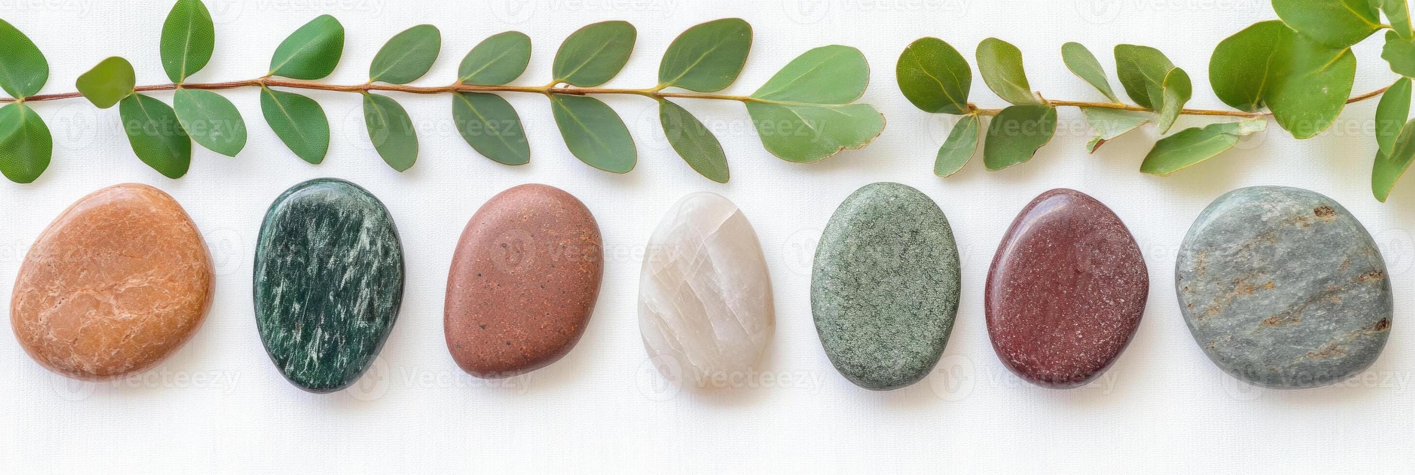 Natural arrangement of rounded green and burgundy stones with greenery on a light background photo