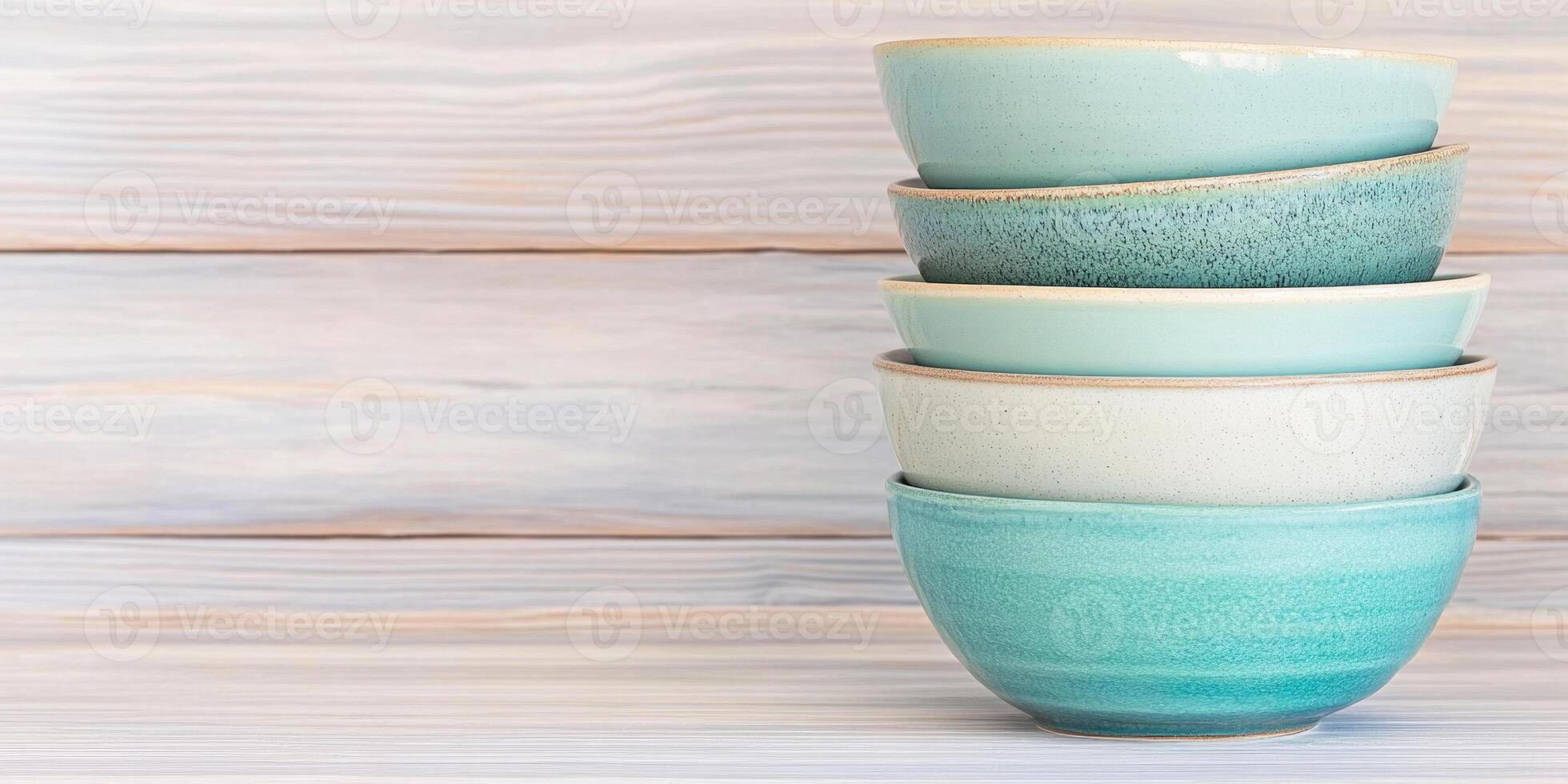 Elegant stacked bowls in teal and green on a rustic wooden table, showcasing minimalist kitchen aesthetics photo