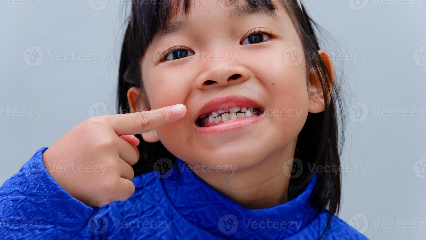 Child touching loose baby tooth, close-up. Baby teeth are replaced by permanent teeth. Children's dentistry, dental care. photo
