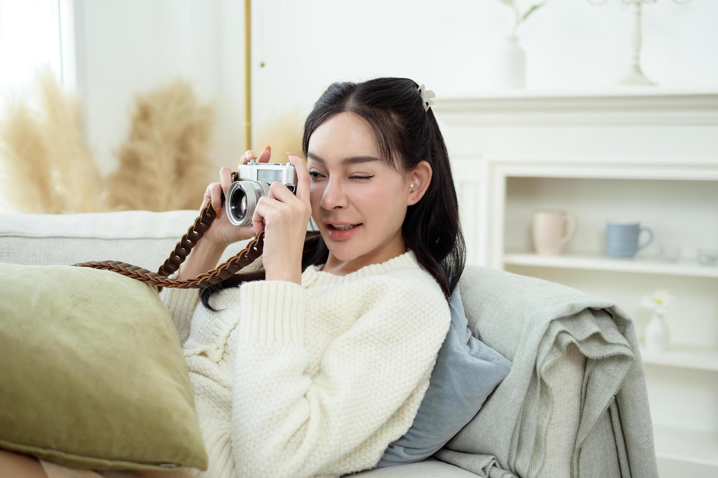 Young Asian smiling woman using camera in living room at home photo