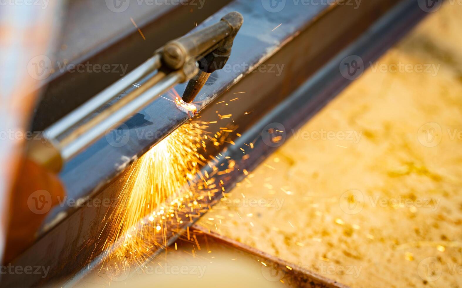 Skilled metalworker uses torch to cut through steel. Sparks fly as craftsman demonstrates precision in industrial workshop. Concept of balancing risk and expertise in dangerous metalworking processes. photo