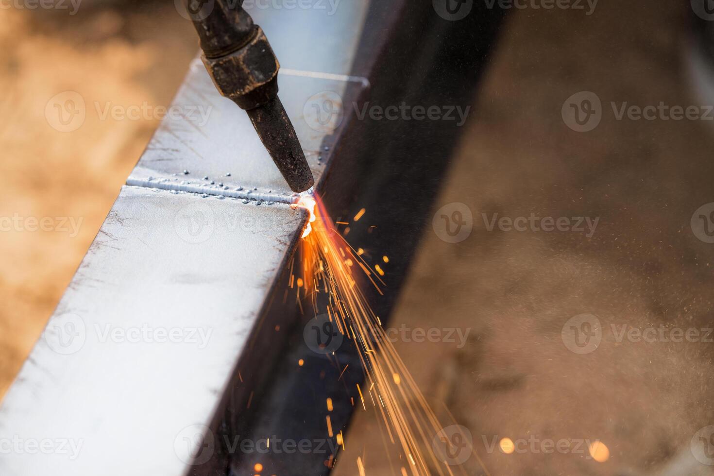 Skilled welder cuts metal with a gas torch in industrial workshop. Sparks fly during precision fabrication process. Craftsman control and expertise in metalworking. Gas torch cuts through steel. photo