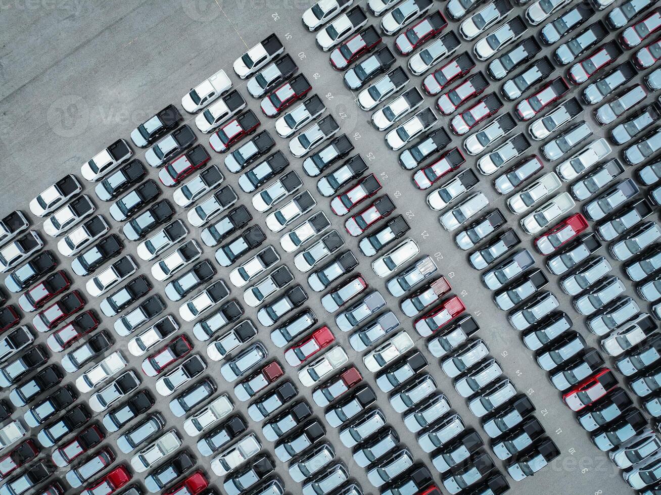 Aerial view of new cars stock at a large factory parking lot. Automotive industry, logistics operations, and vehicle storage for import and export. Key role in the global car market supply chain. photo