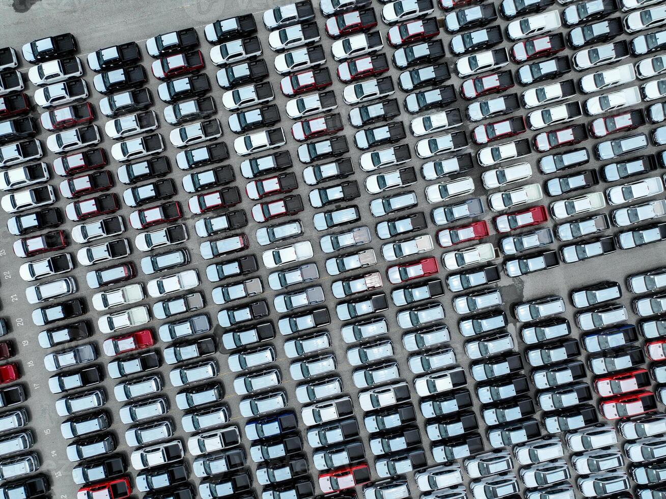 Aerial view of new cars stock at a large factory parking lot. Automotive industry, logistics operations, and vehicle storage for import and export. Key role in the global car market supply chain. photo