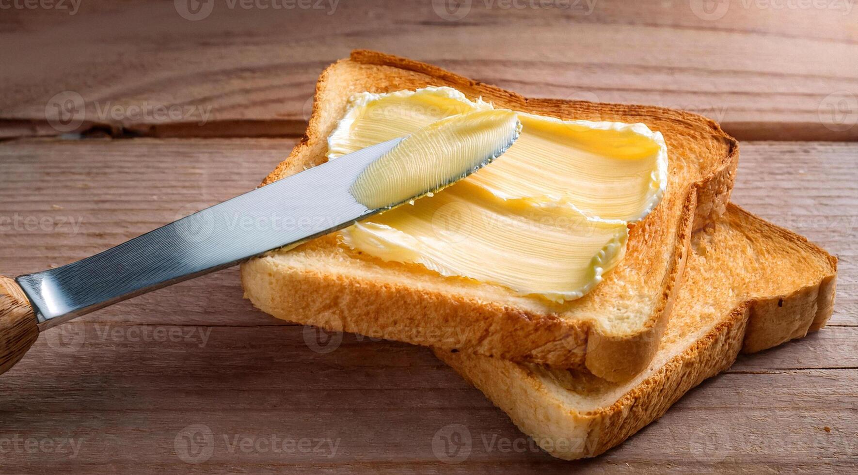 Knife spreading butter on toast bread on wooden background photo