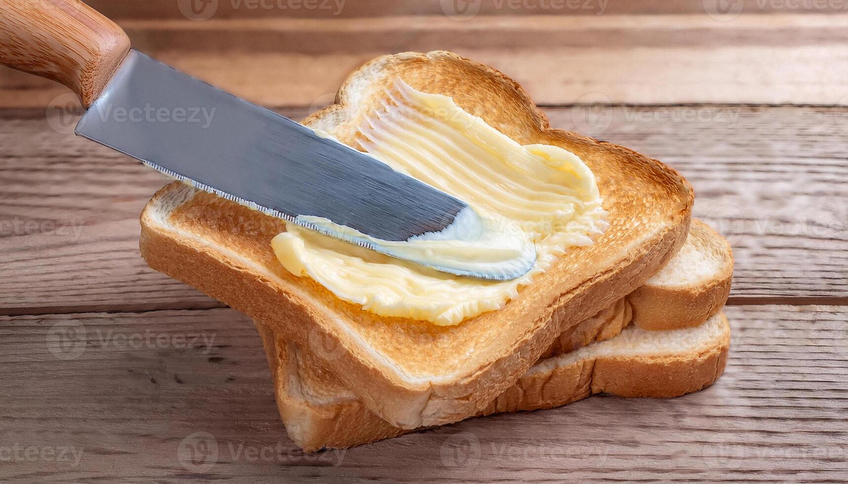 Knife spreading butter on toast bread on wooden background photo