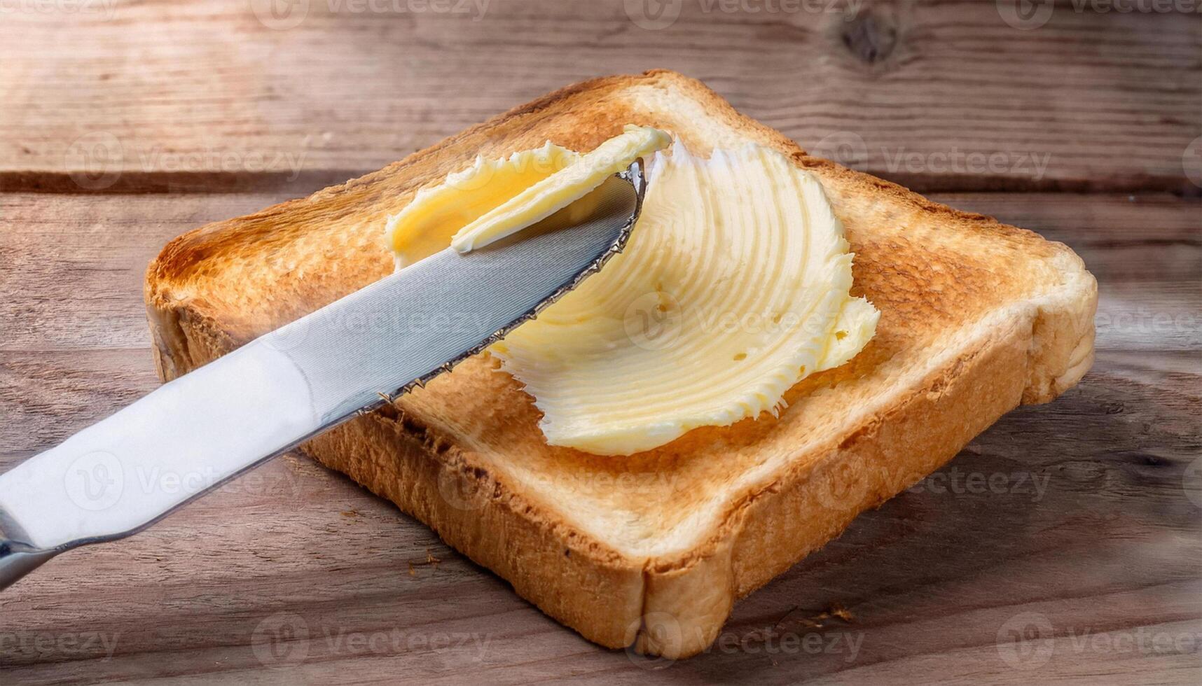Knife spreading butter on toast bread on wooden background. photo