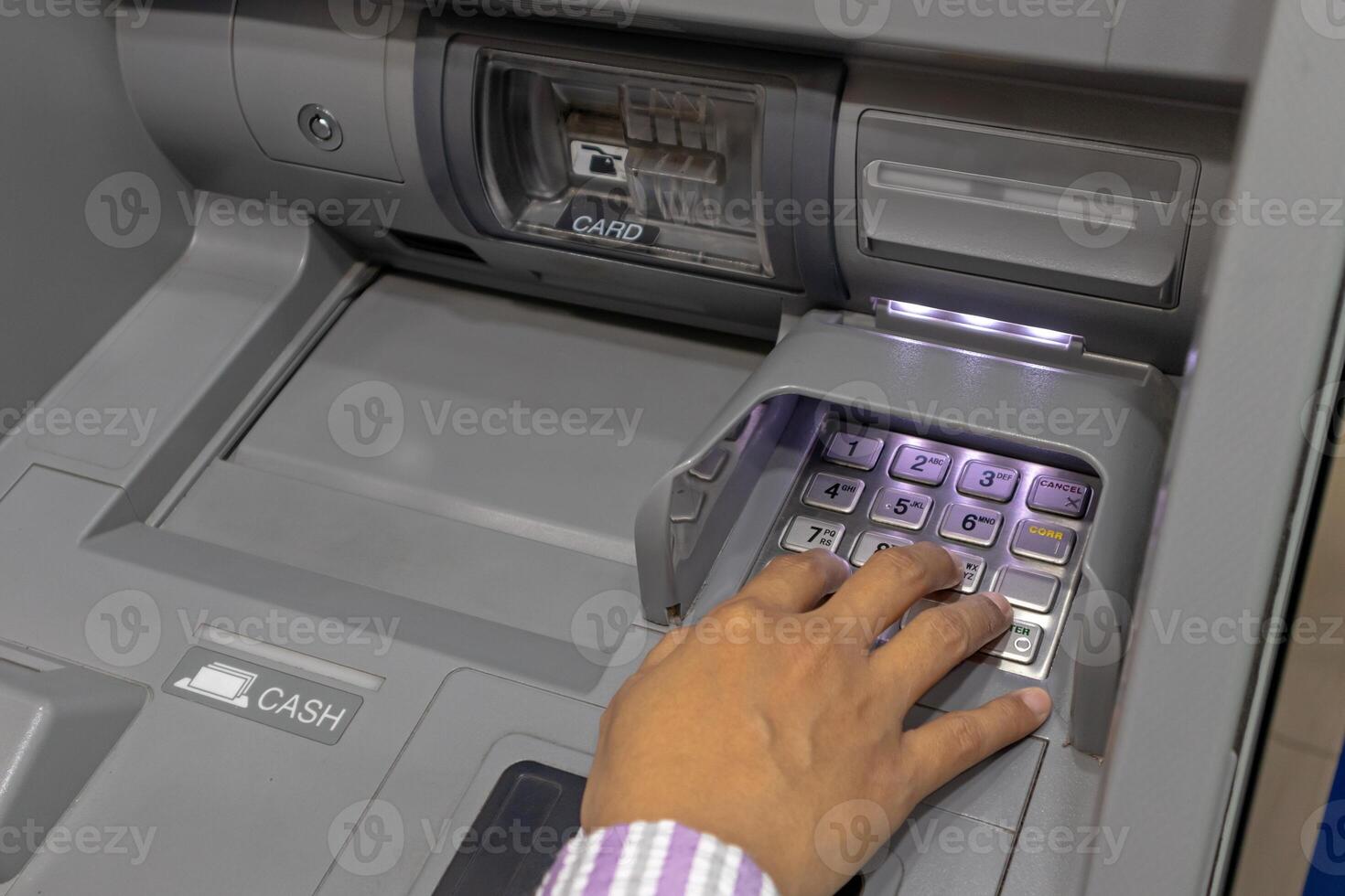 Close up view of a female hand pressing number keys on Automated Teller Machine or ATM machine photo