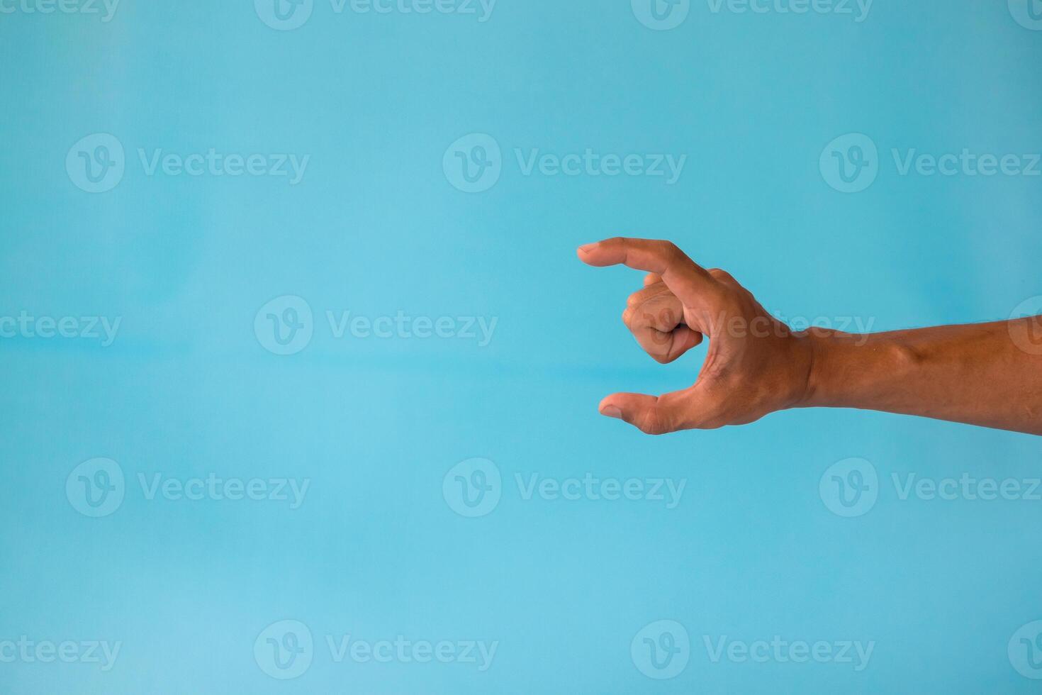 A man's hand with a pose or gesture of holding or showing something on a blue background photo