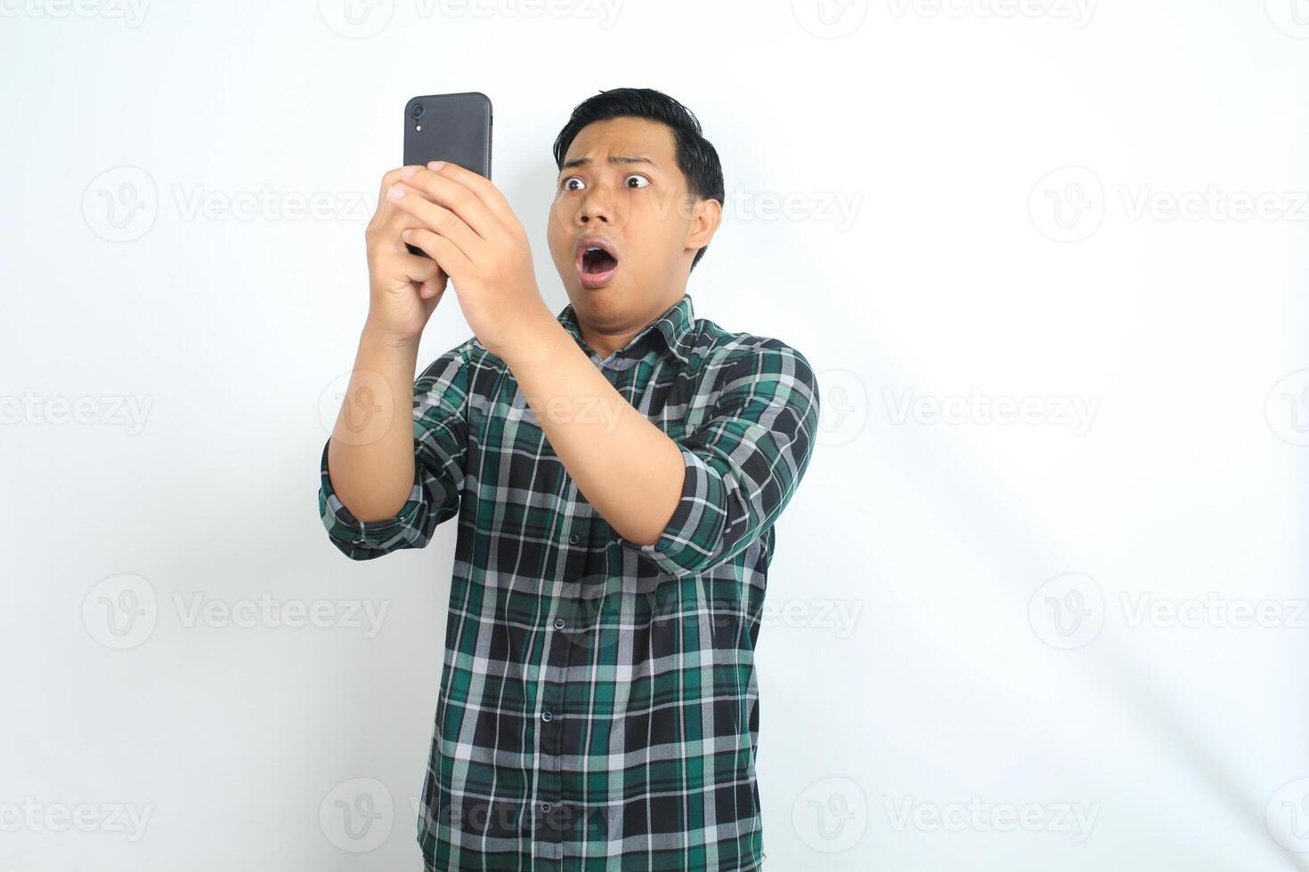 shocked asian man looking at smartphone show confused expression isolated on white background photo