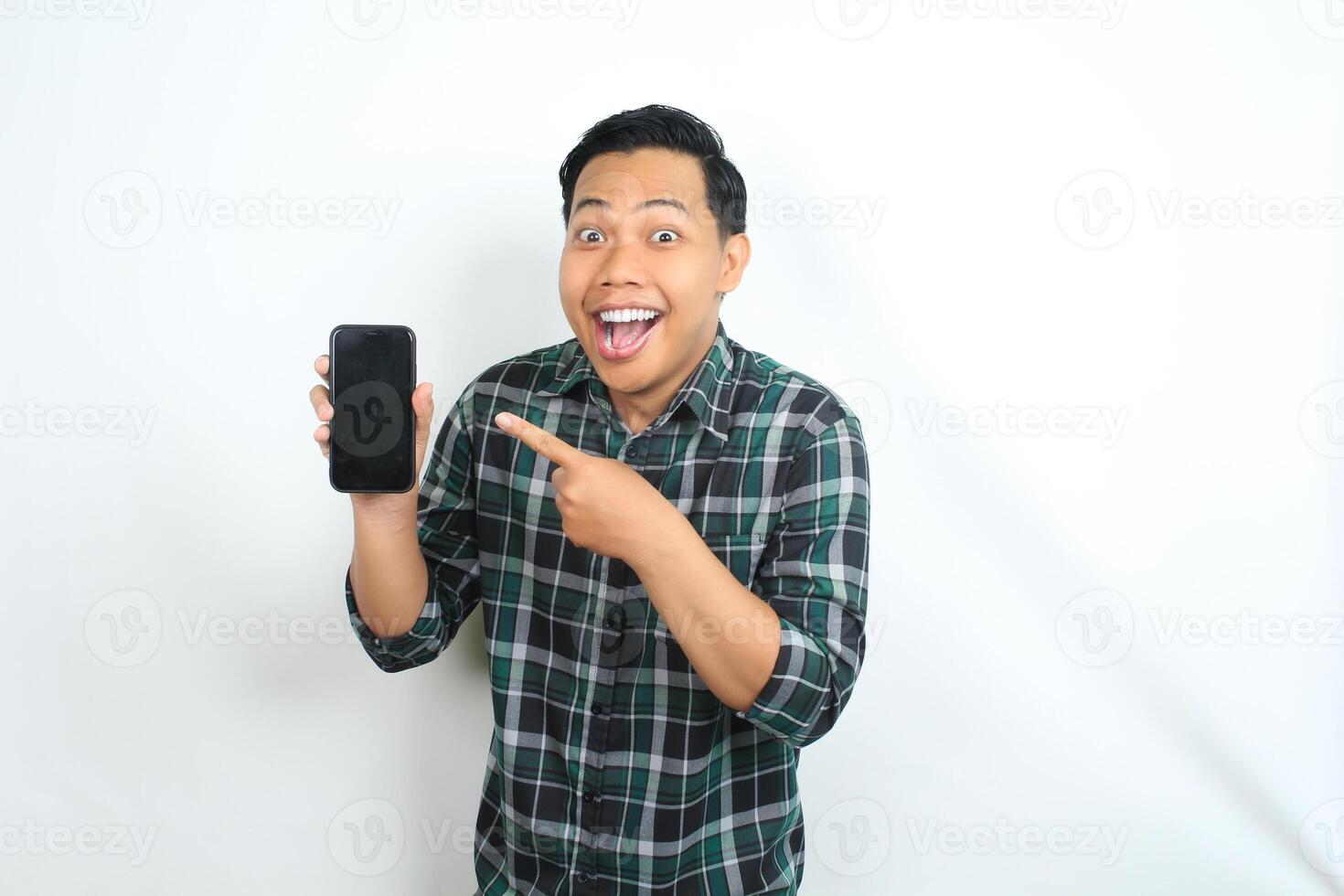 cheerful and excited asian man pointing smartphone screen with surprised face isolated on white background photo