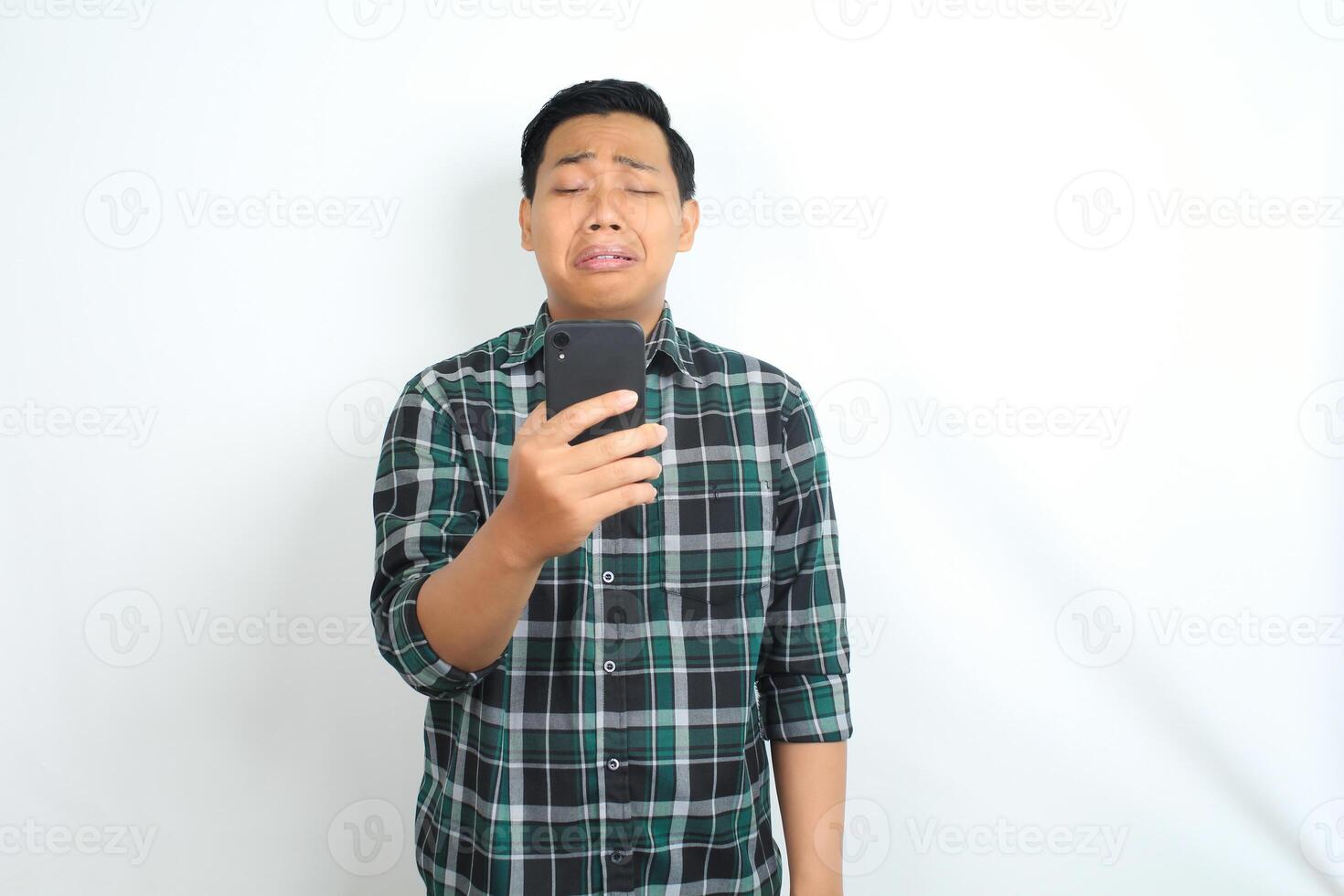 sad asian man wearing casual plaid shirt crying while read bad message on smartphone isolated on white background photo