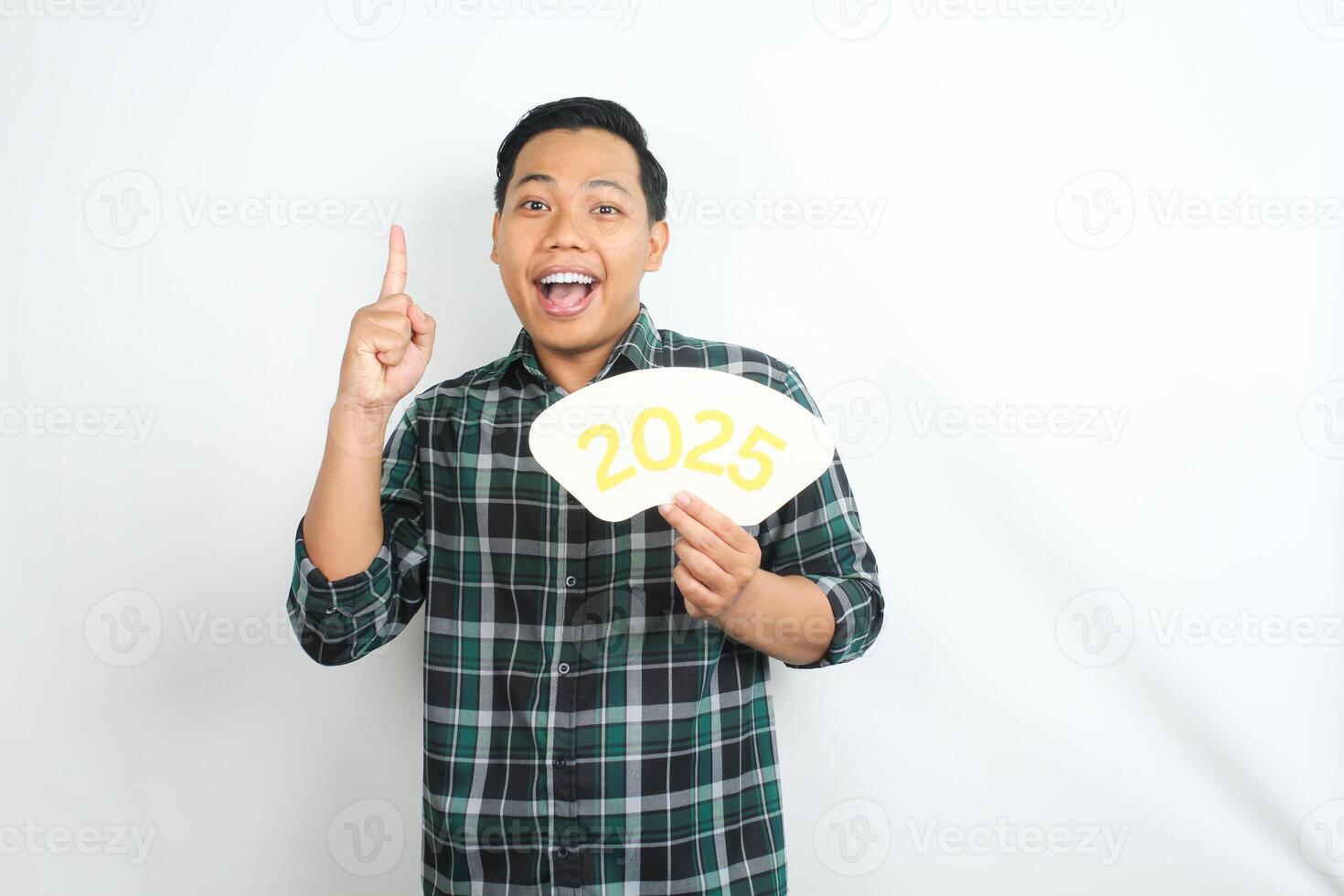 surprised asian young adult man holding 2025 new years eve greeting card with pointing finger isolated on white background photo