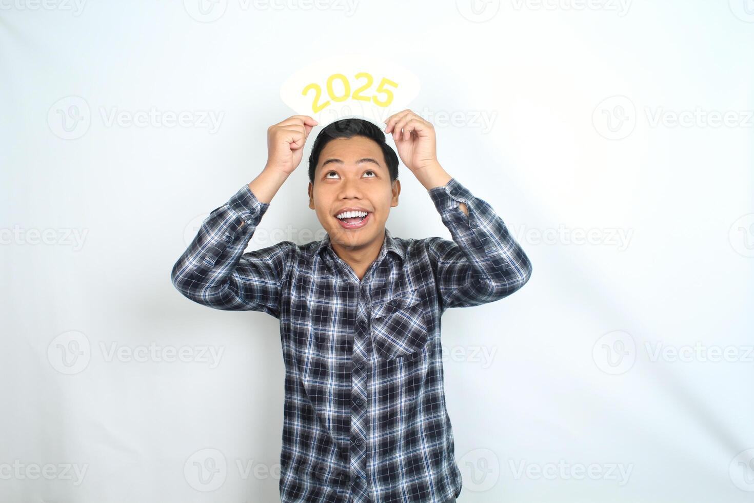 attractive asian man smiling with holding 2025 card and looking above to celebrate new year eve isolated on white background photo