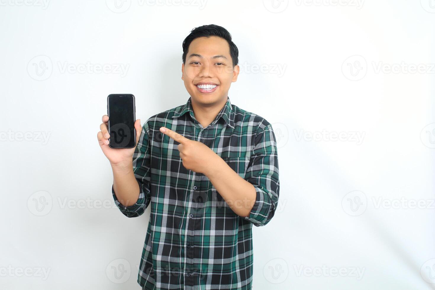 attractive asian man smiling happy while showing smartphone screen with pointing hands isolated on white background photo