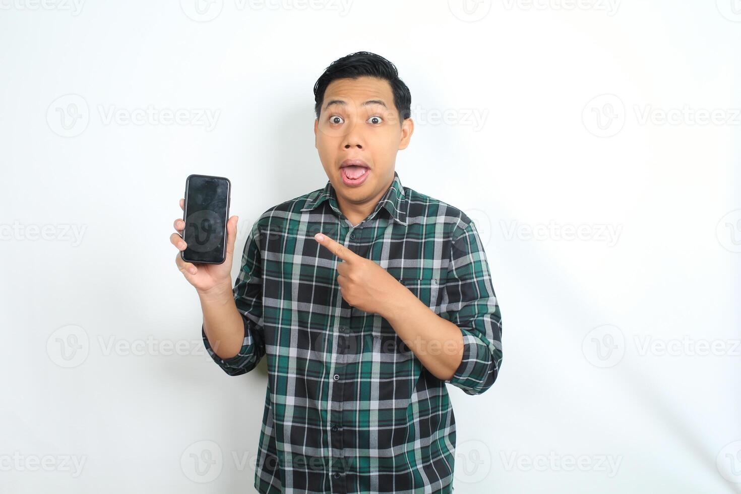 cheerful and excited asian man pointing smartphone screen with surprised face isolated on white background photo