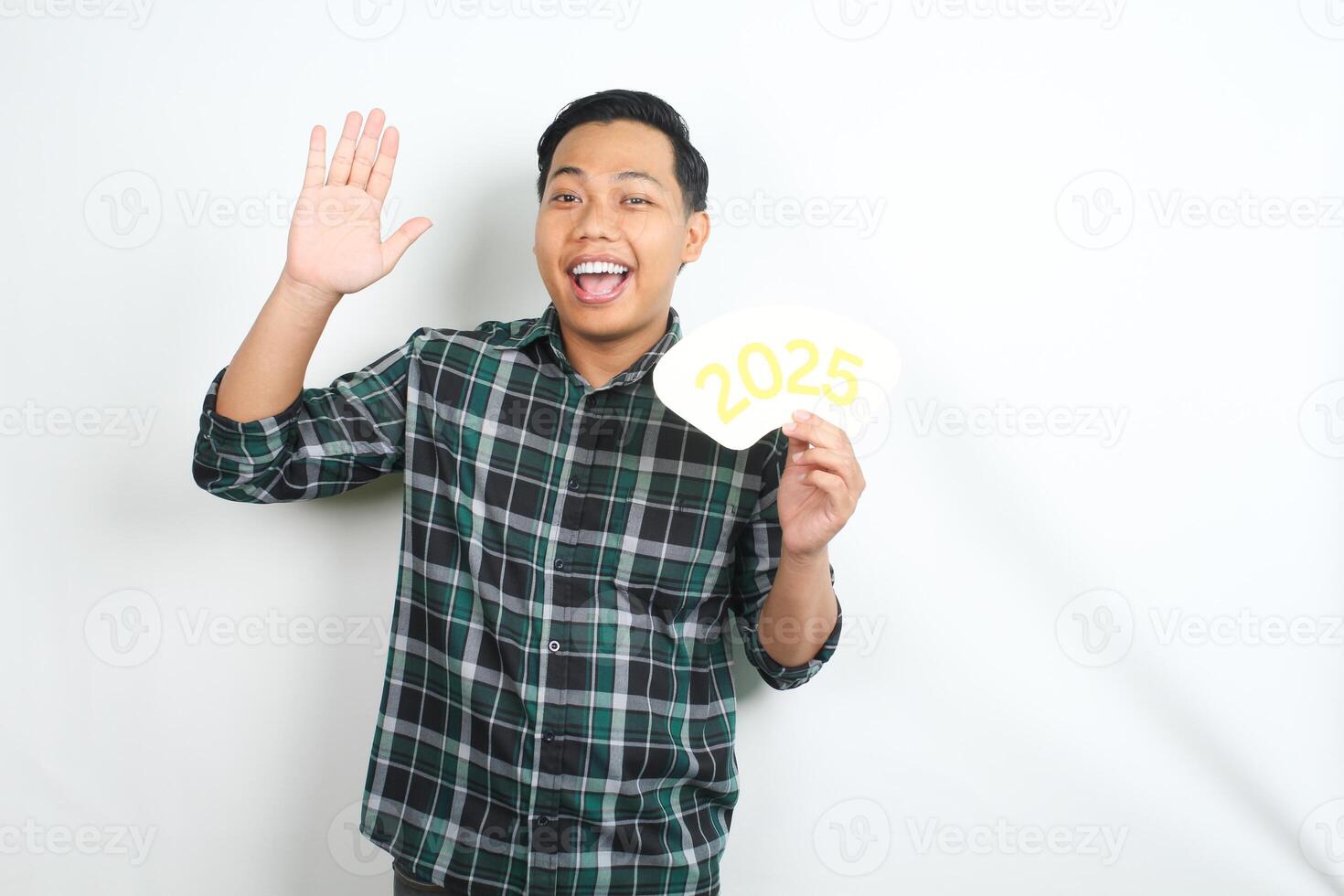 carefree asian young man holding 2025 new years eve card and waving hand to camera isolated on white background photo