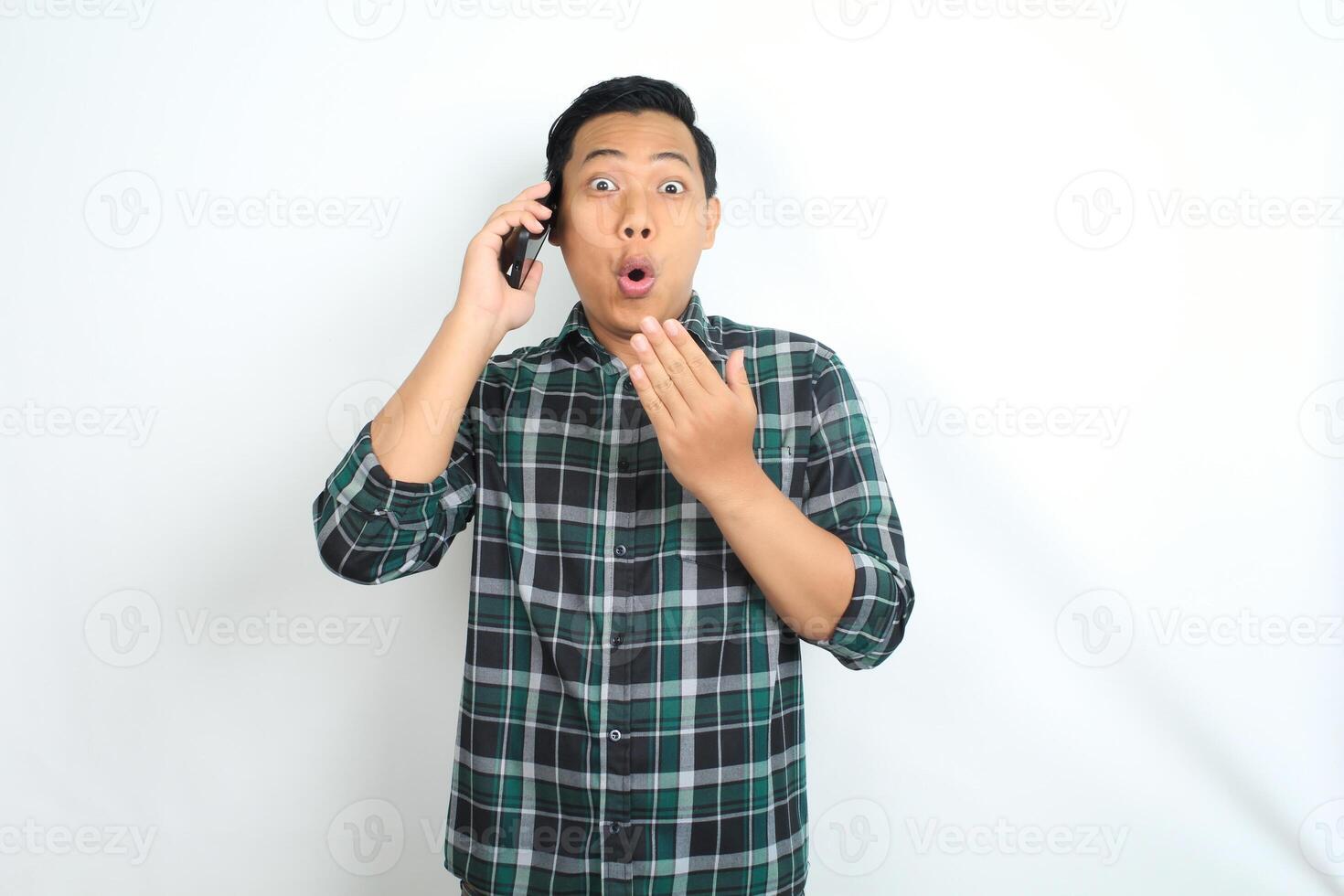 asian man shocked while talking on cellphone isolated on white background photo