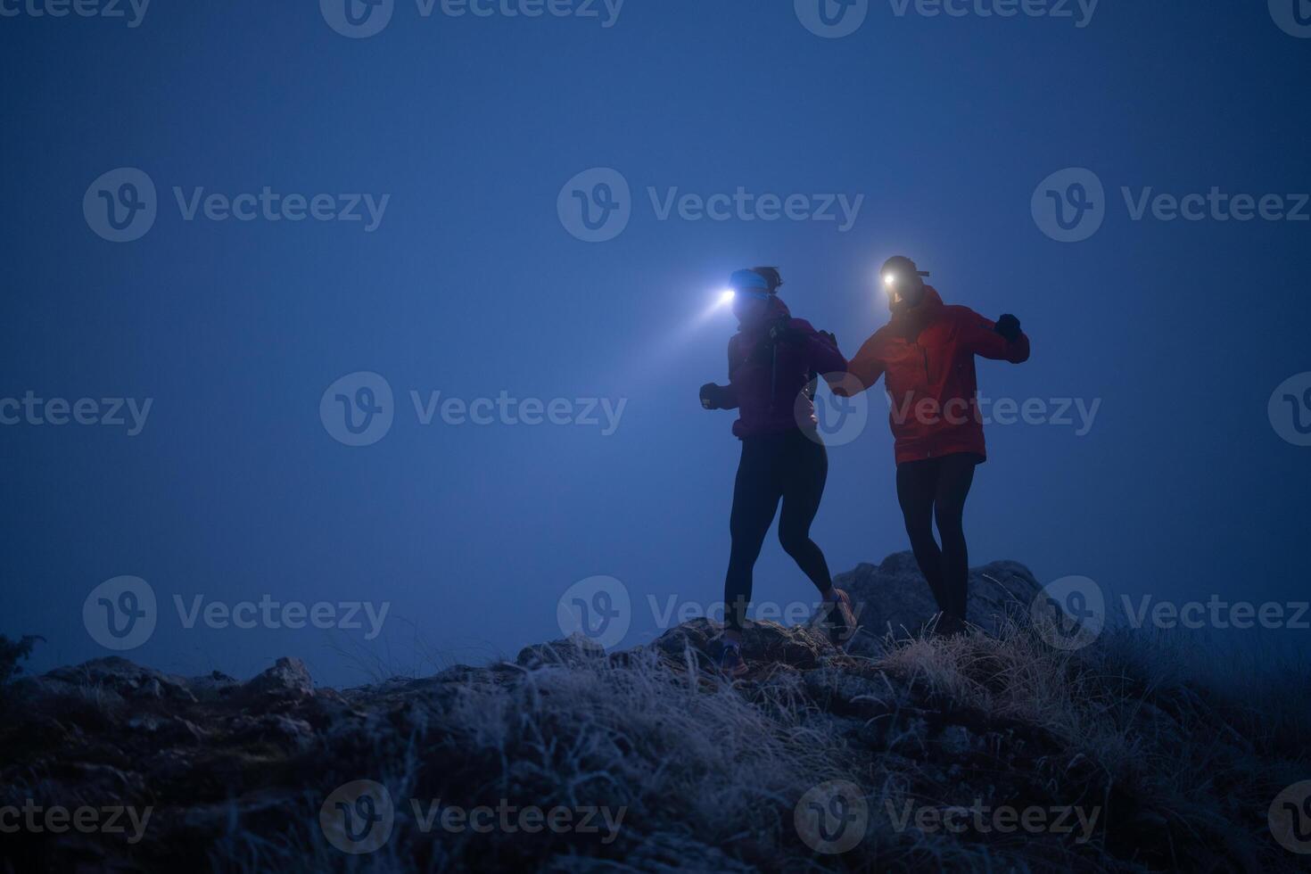 Night trail runner of men and women running on the mountain.at night milky way photo