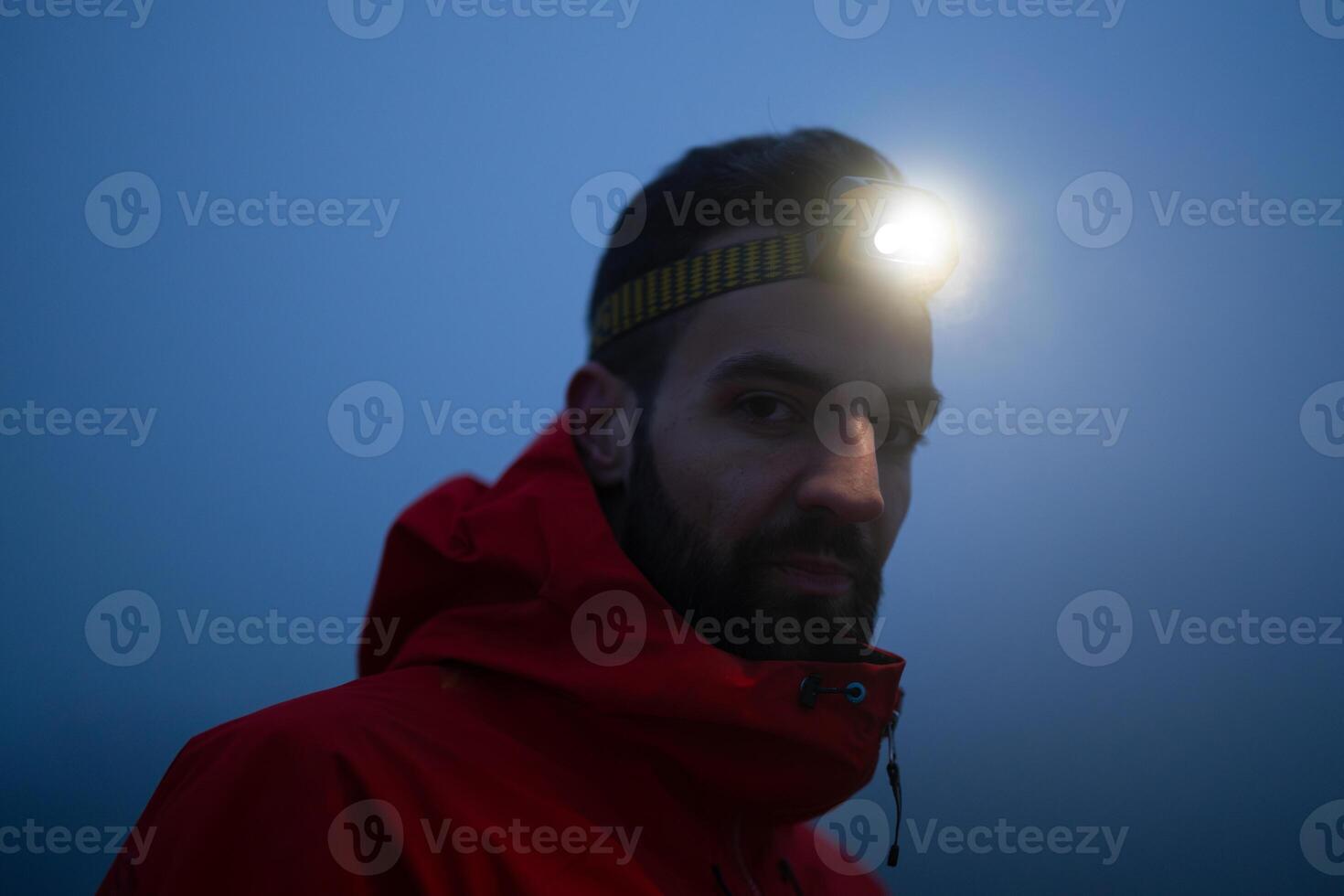 Hiker or triathlon trail runner with a headlamp on a trail in the mountain with fog at night photo